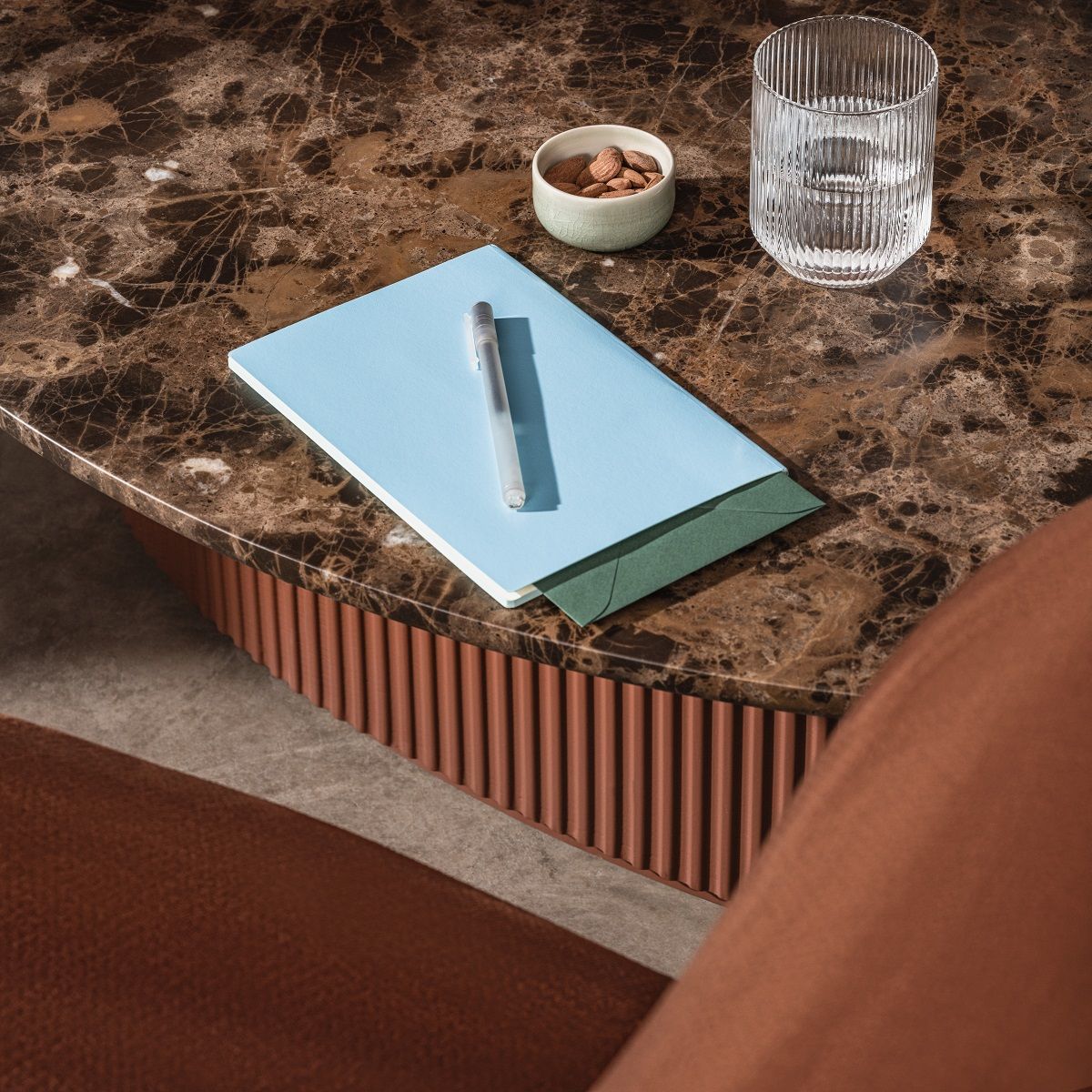 Bolete Couchtisch von Andreu World mit Marmorplatte, Notizbuch, Stift, Wasserglas und Mandeln.