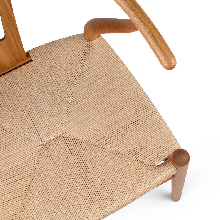 Detailaufnahme des CH24 Wishbone Chair Stuhls von Carl Hansen & Søn mit Teakholzrahmen und geflochtener Sitzfläche.
