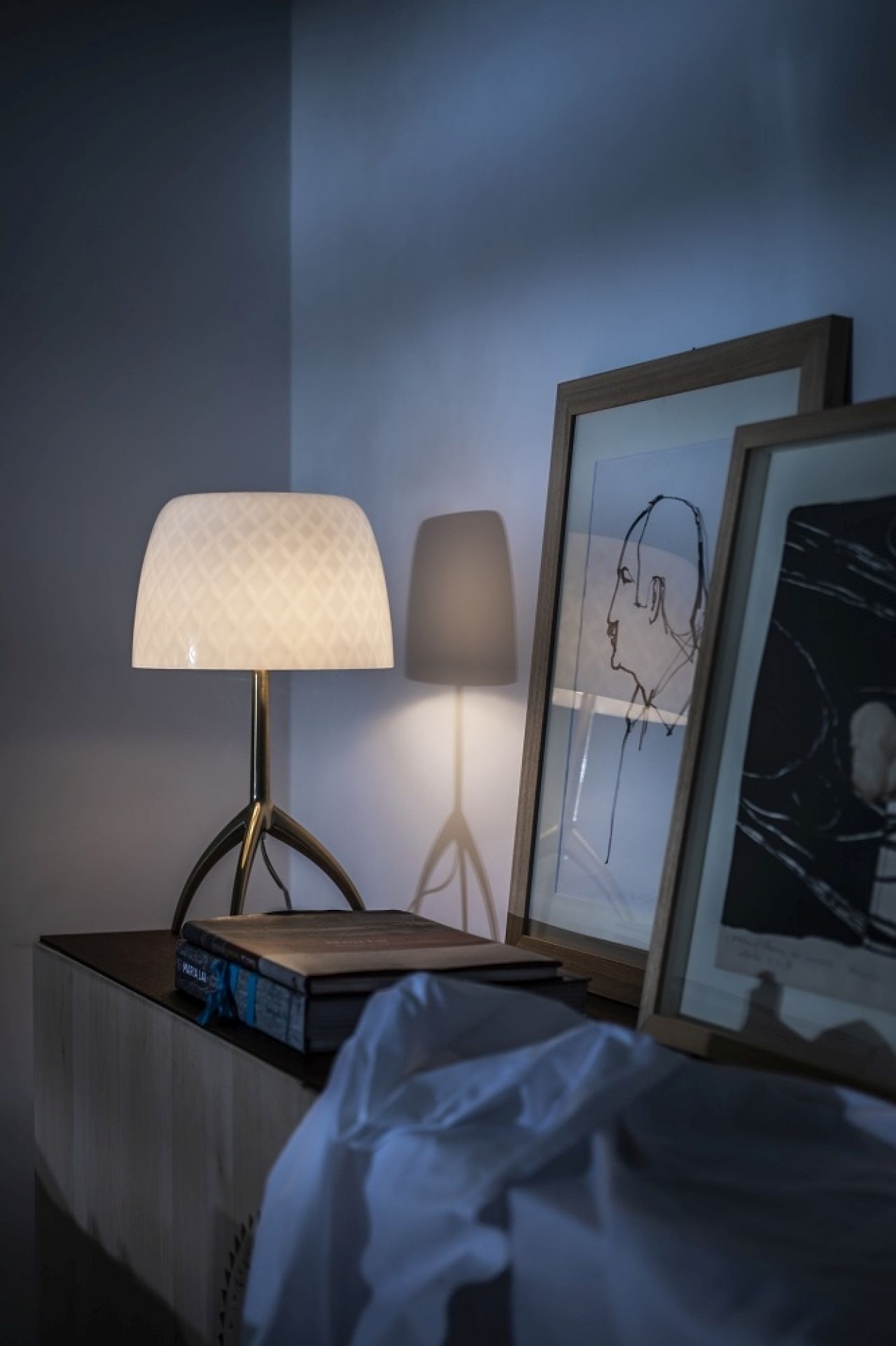 Lumiere Tischleuchte von Foscarini auf Kommode mit Kunstwerken, stimmungsvolle Beleuchtung für Wohnzimmer und Schlafzimmer.