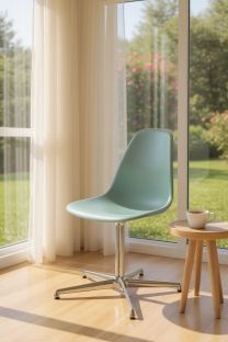Mintgrüner Eames Fiberglass Side Chair DSL Stuhl von Vitra neben einem Fenster mit Gartenblick.