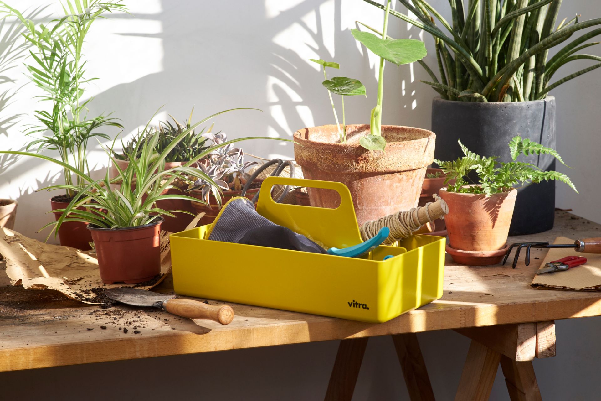 Gelbe Vitra Toolbox Organisationsbox mit Gartenzubehör und Pflanzen auf einem Holztisch, ideal für Gartenarbeit und Aufbewahrung.