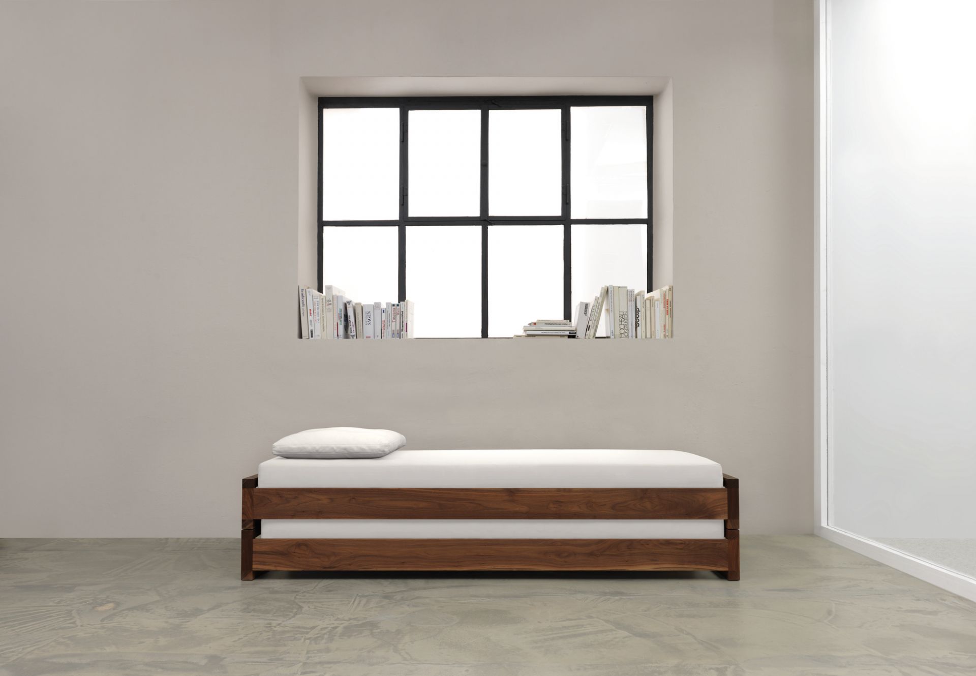 Guest 90 Holzbett: Modernes Einzelbett aus massivem Nussbaumholz mit weißer Matratze und Kissen.