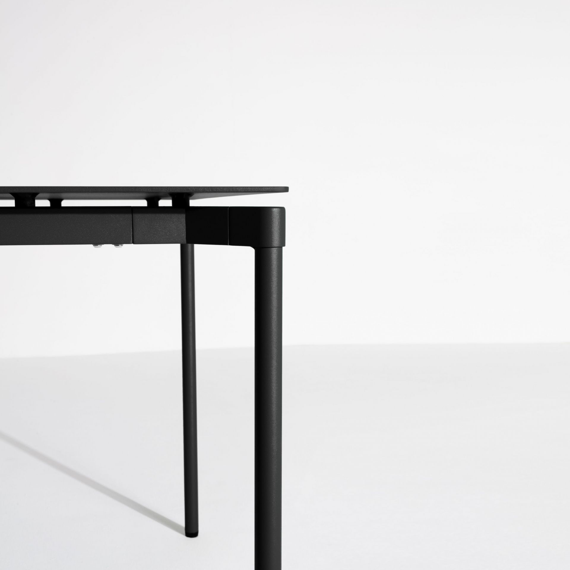 Detailaufnahme des Fromme Esstischs von Petite Friture: Rechteckige Tischplatte und Tischbeine in Schwarz.