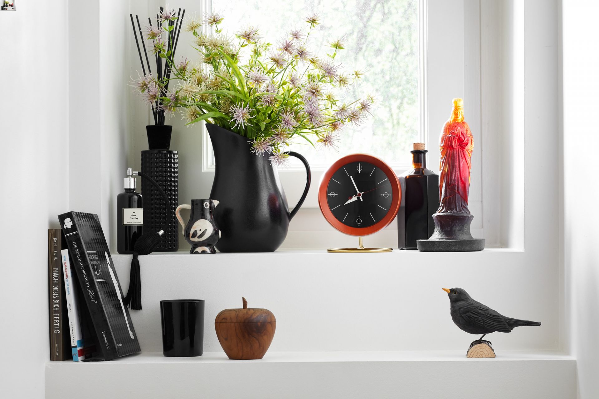 Nahaufnahme der Vitra Chronopak Tischuhr in Orange, Teil einer Dekoration auf einem weißen Regal.