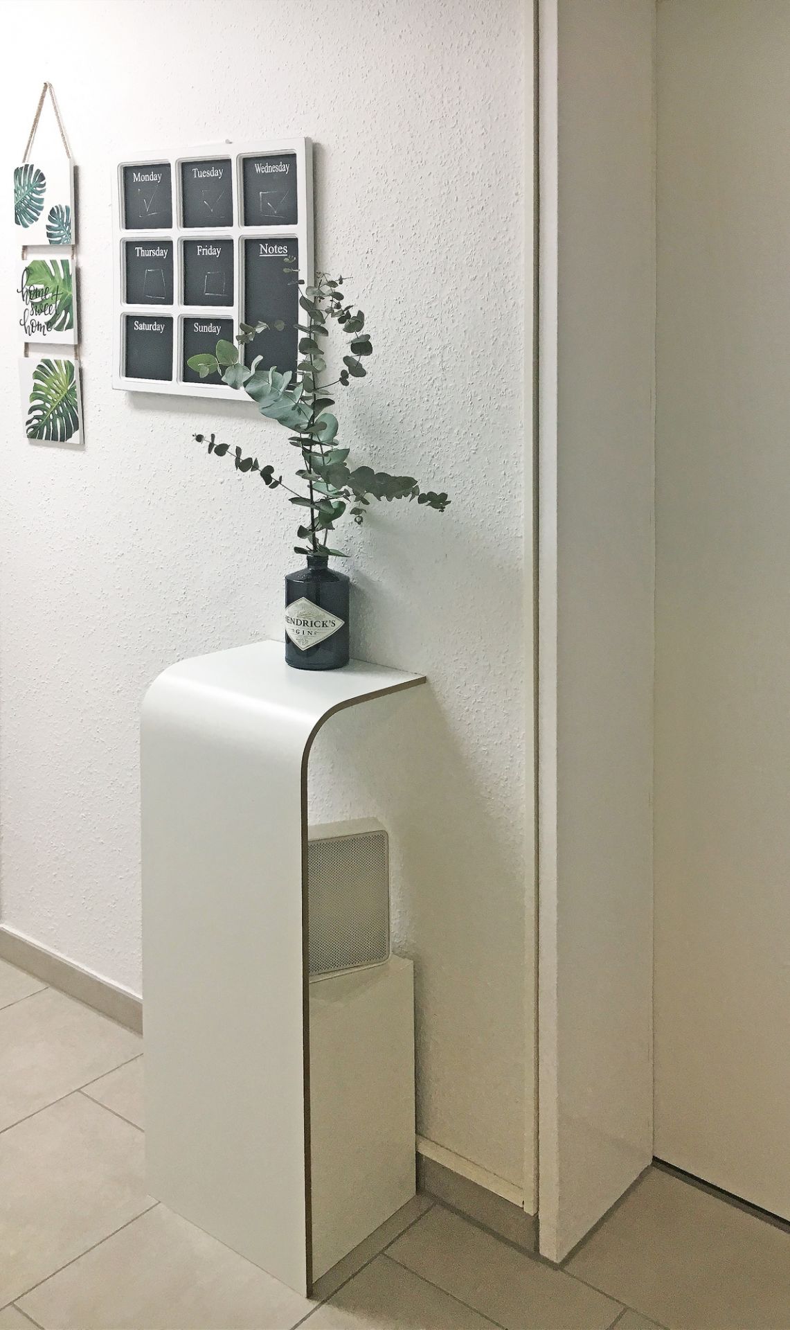 Weißes Tojo Fon Regal mit abgerundeten Kanten, dekoriert mit Gin-Flasche und Eukalyptus, minimalistisches Design.