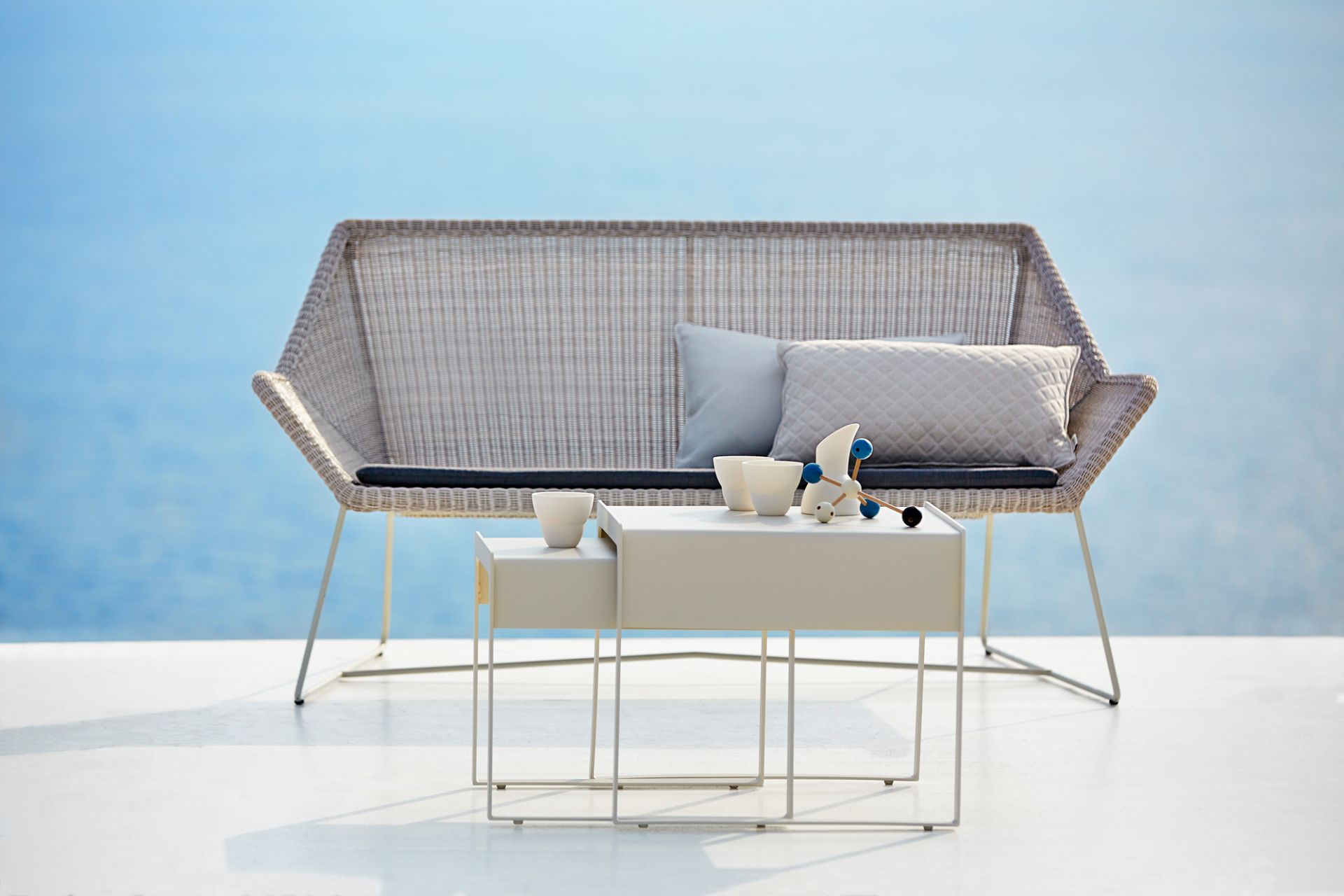 Breeze Loungesofa von Cane-Line: Graues Outdoor Sofa mit Kissen und Beistelltisch.