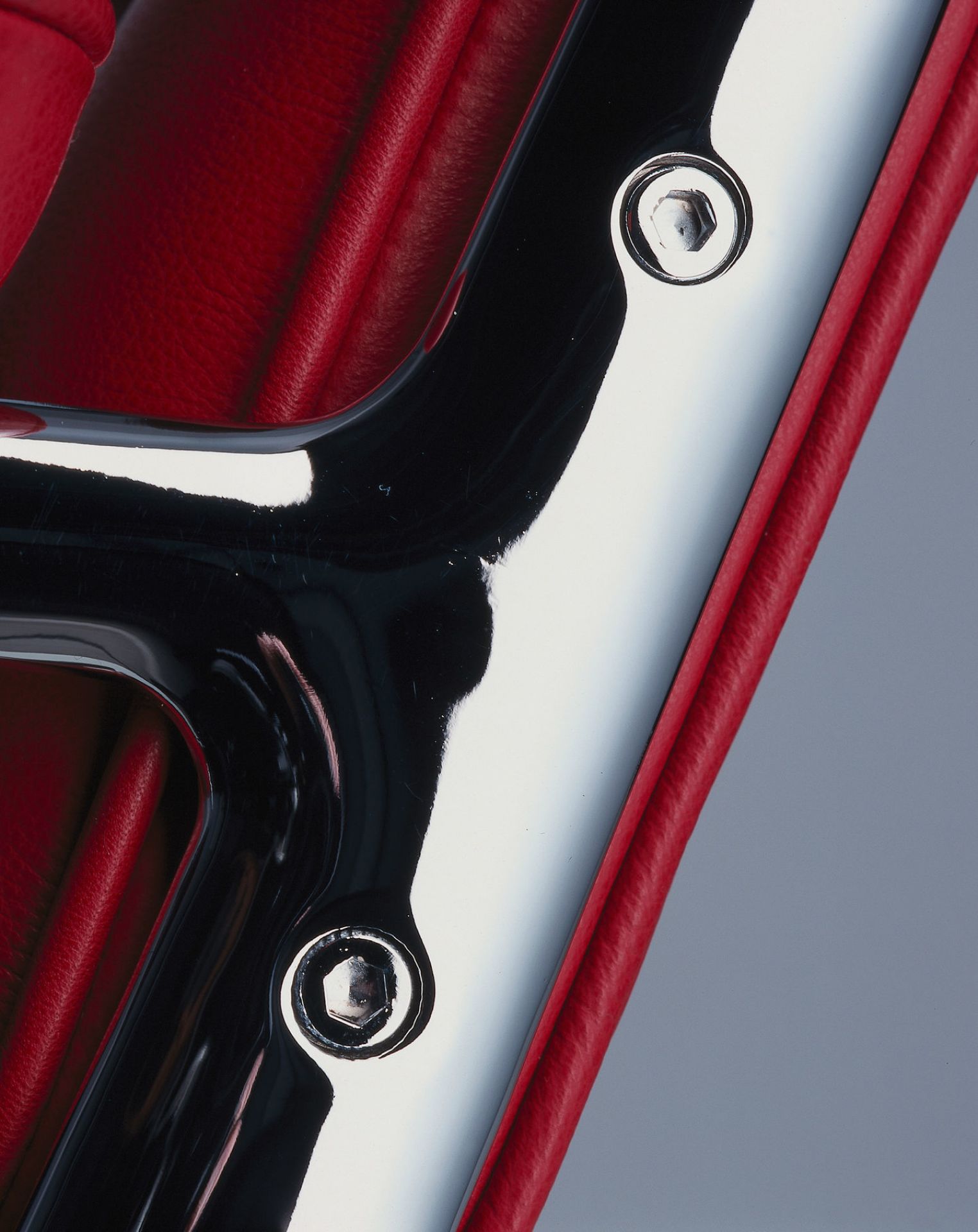 Detailaufnahme: Rotes Leder und Chrom des Vitra Lobby Chair ES 105 Stuhls.