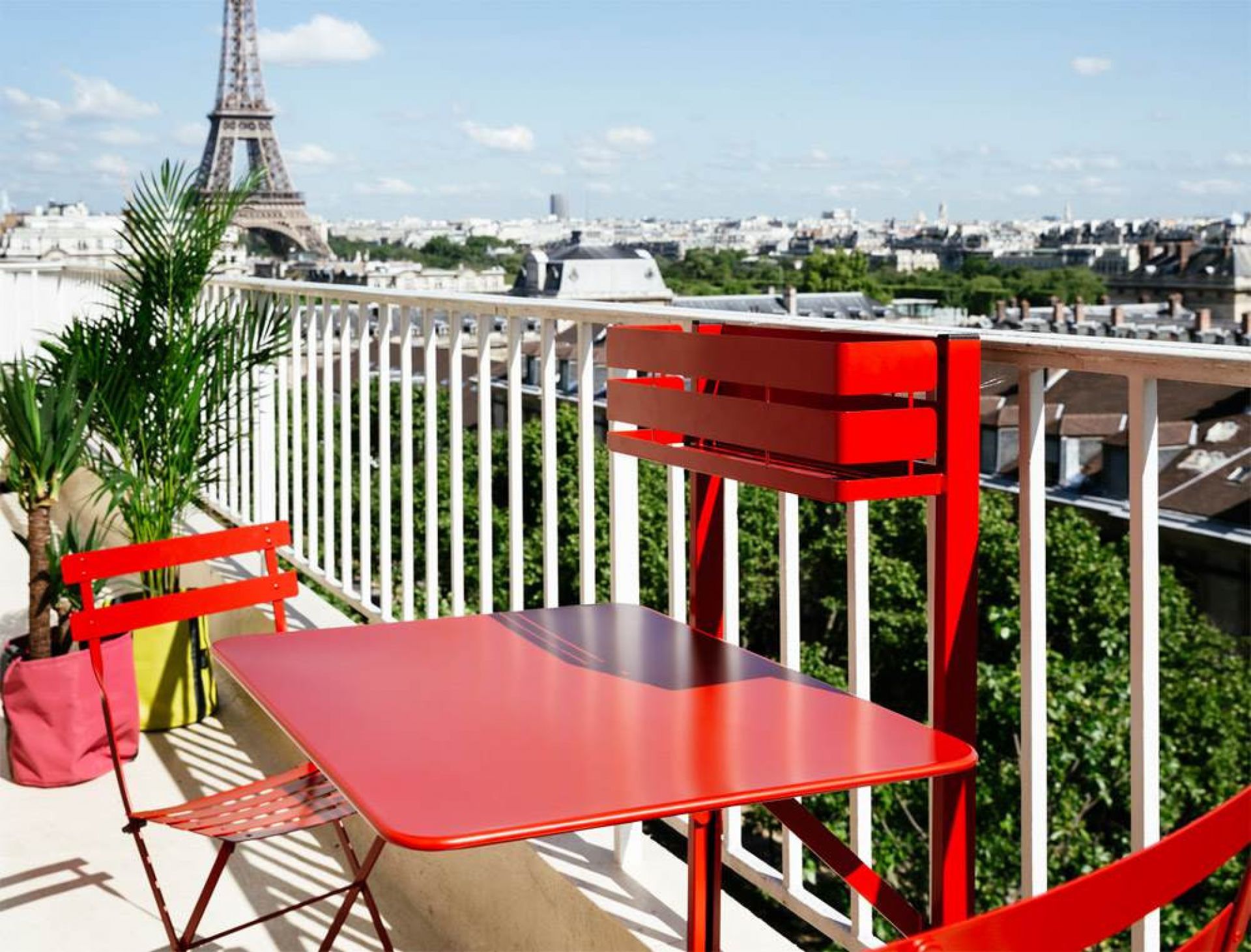 Roter Bistro Balkontisch von Fermob mit Stühlen auf einem Balkon mit Blick auf Paris.