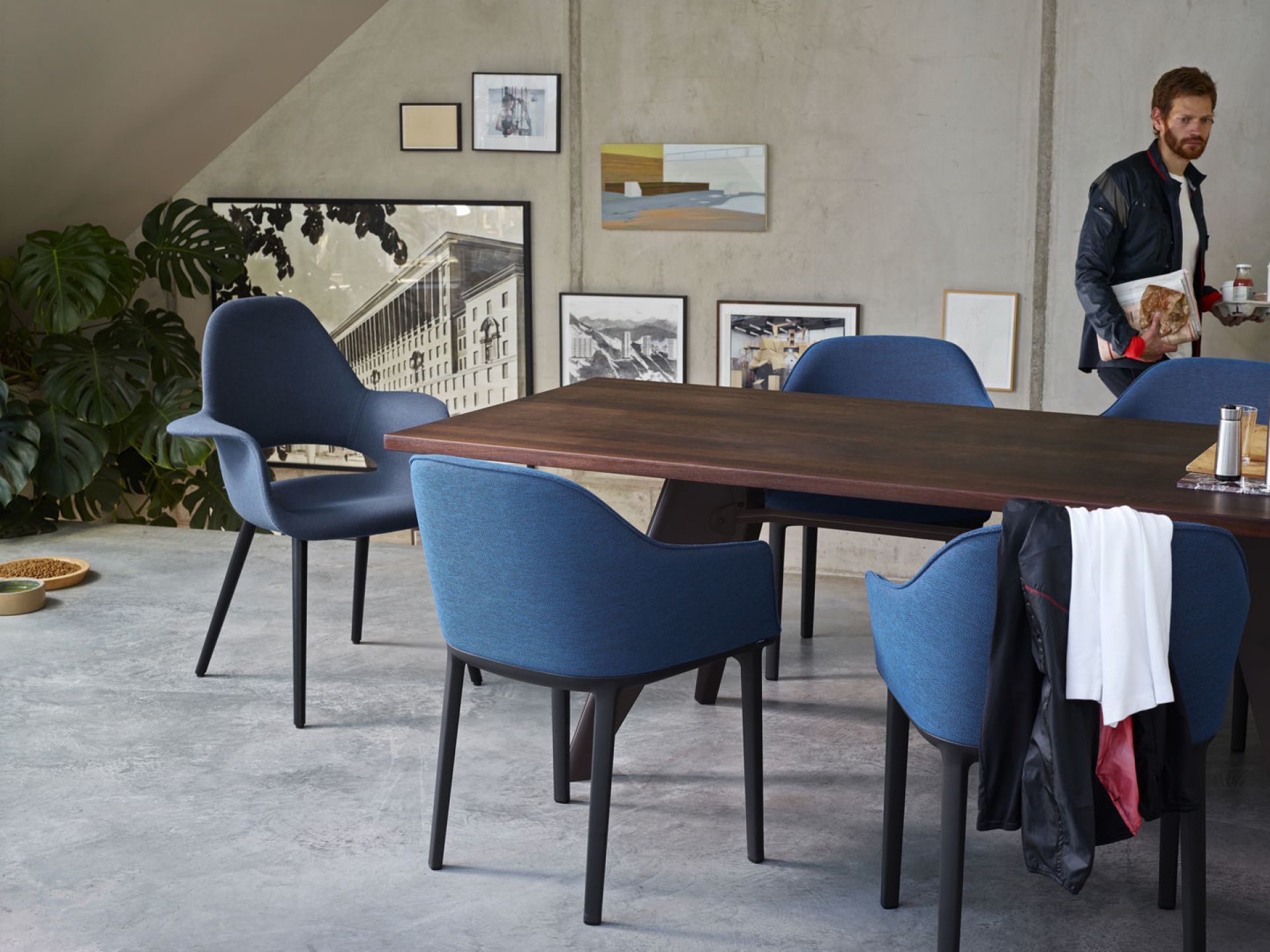 Blauer Organic Conference Stuhl von Vitra um einen dunklen Holztisch in modernem Büro.