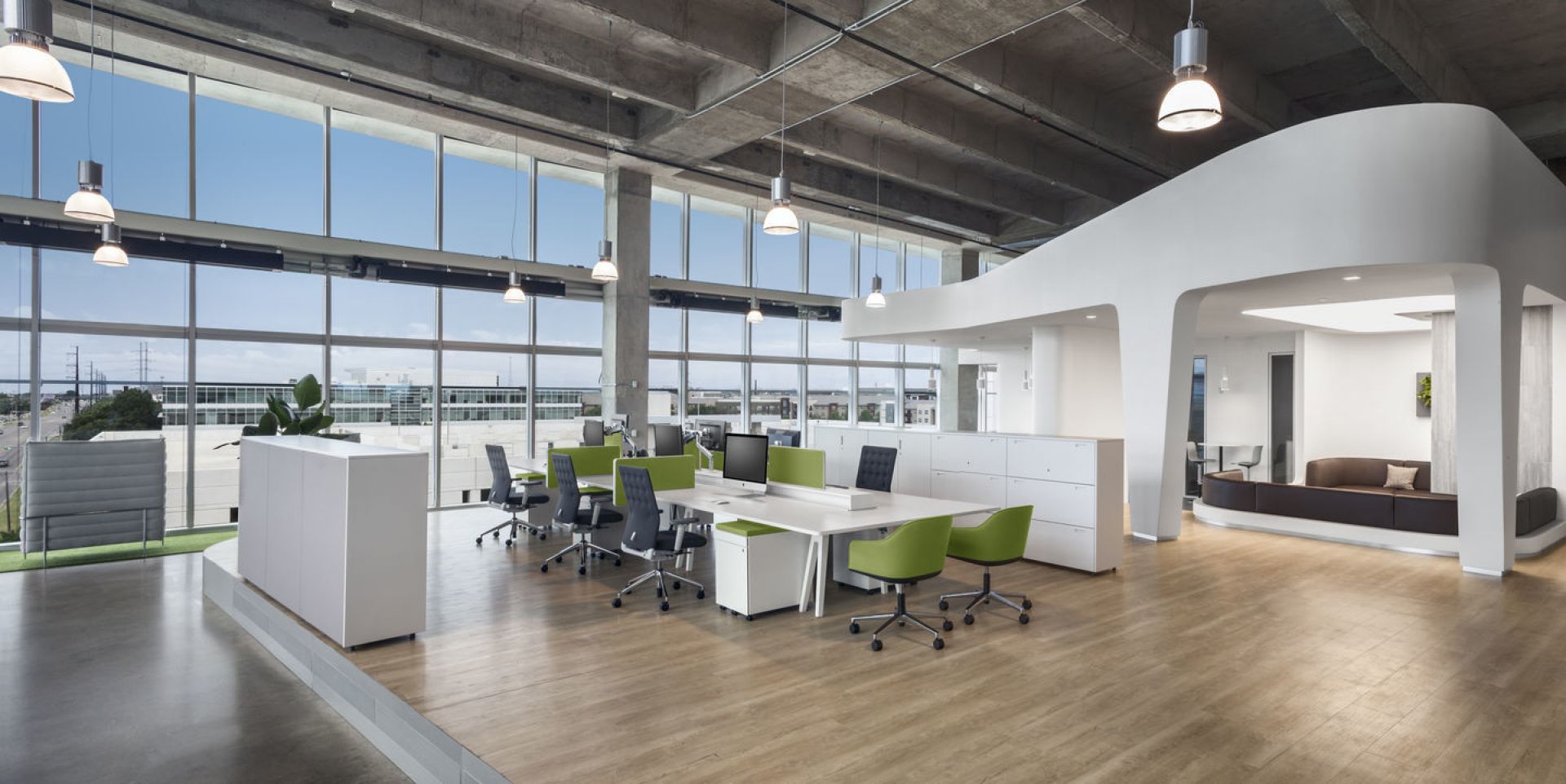 Helles Großraumbüro mit weißen Tischen und grünen Vitra Softshell Chairs mit Fünfsternfuß als Drehstuhl.