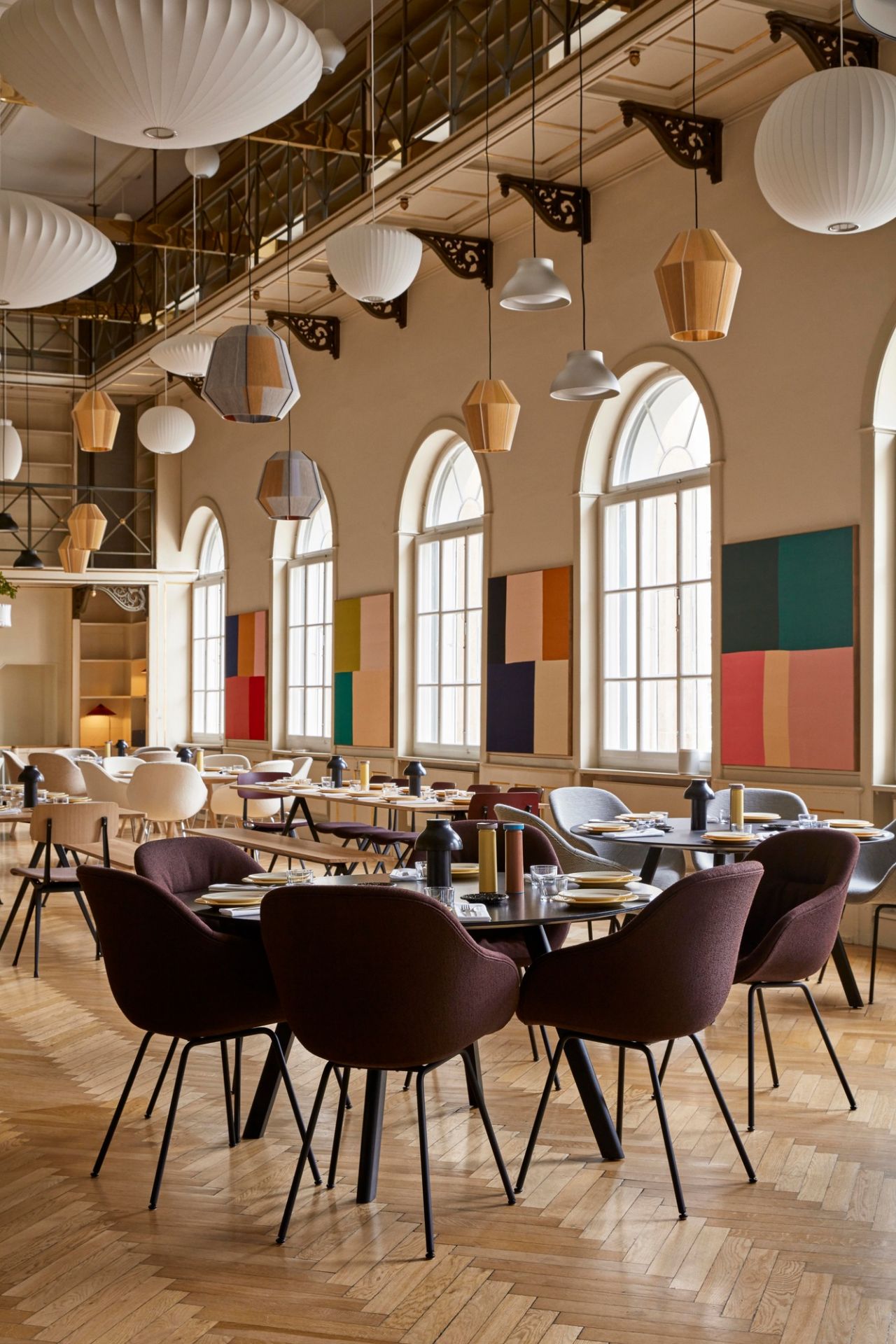 Innenansicht eines Restaurants mit mehreren Tischen und braunen About a Chair AAC127 Stühlen von Hay.