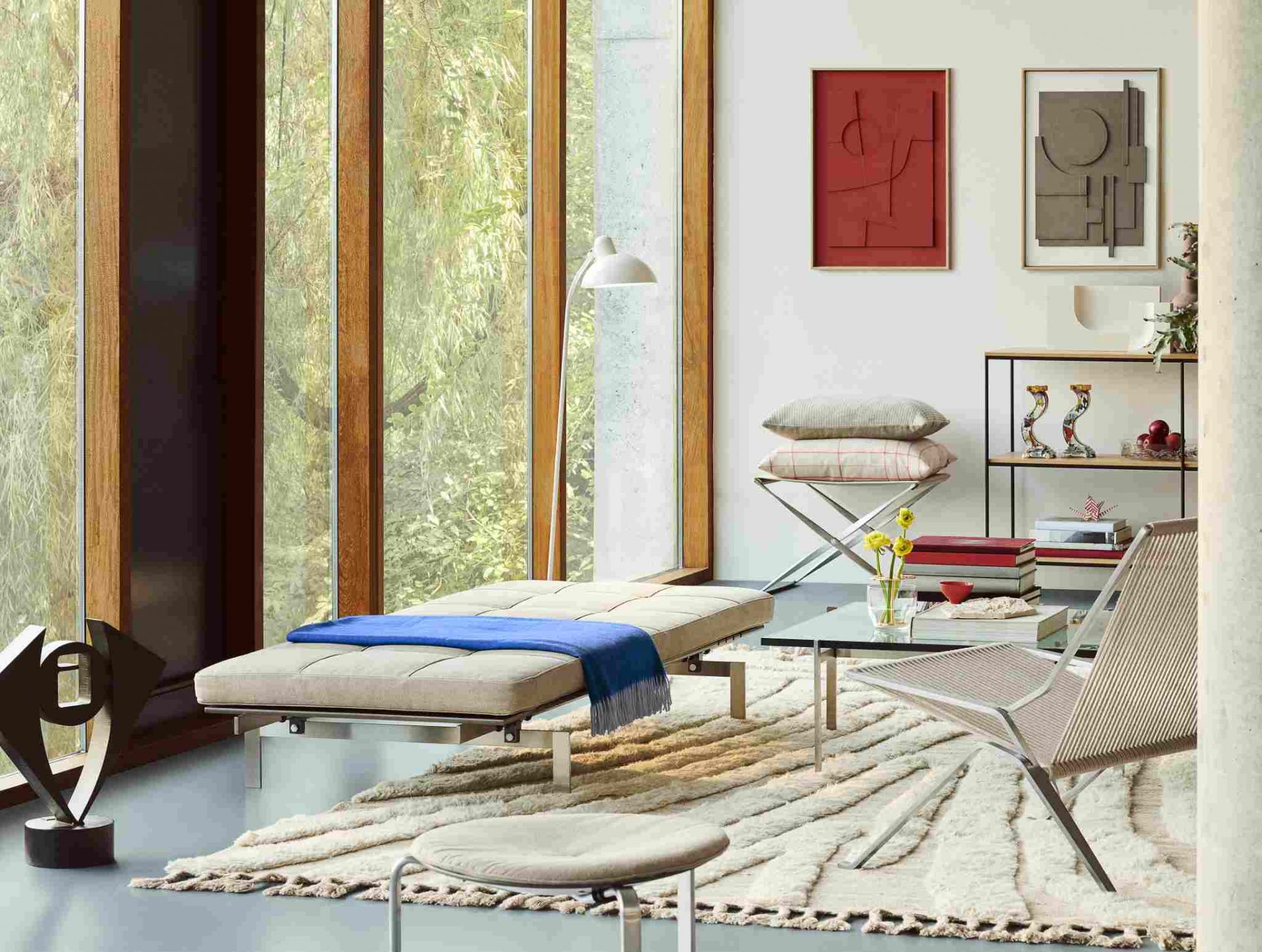 Heller Wohnraum mit PK25 Sessel von Fritz Hansen, Liege mit blauer Decke und Design-Dekoration.