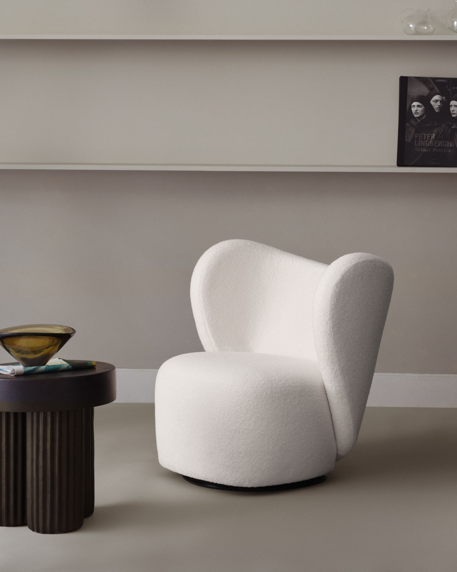 Gear Tall Side table von Norr11 aus dunklem Holz neben einem weißen Sessel.