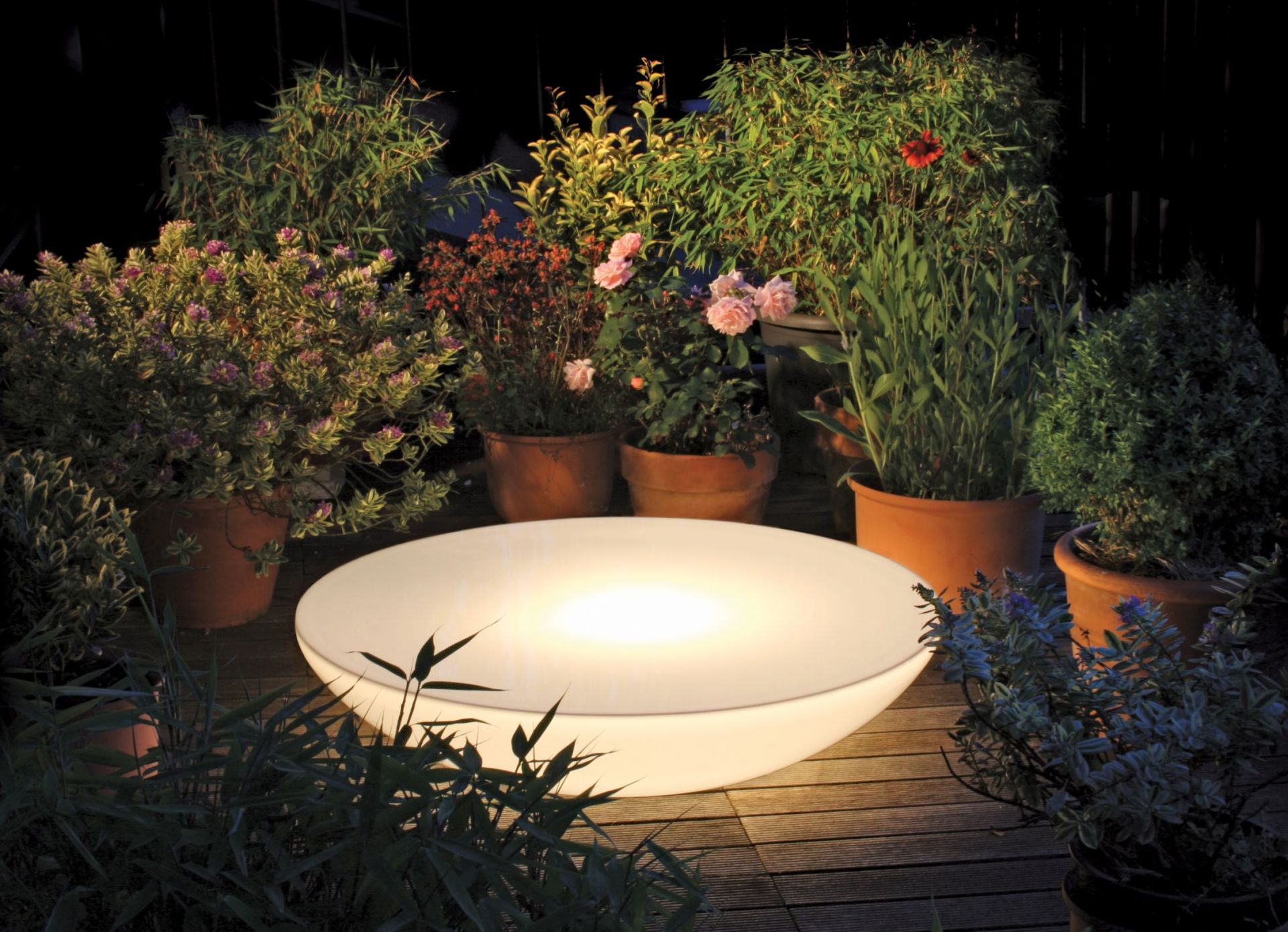 Moree Lounge Beistelltisch Outdoor LED leuchtet auf einer Terrasse mit Pflanzen.