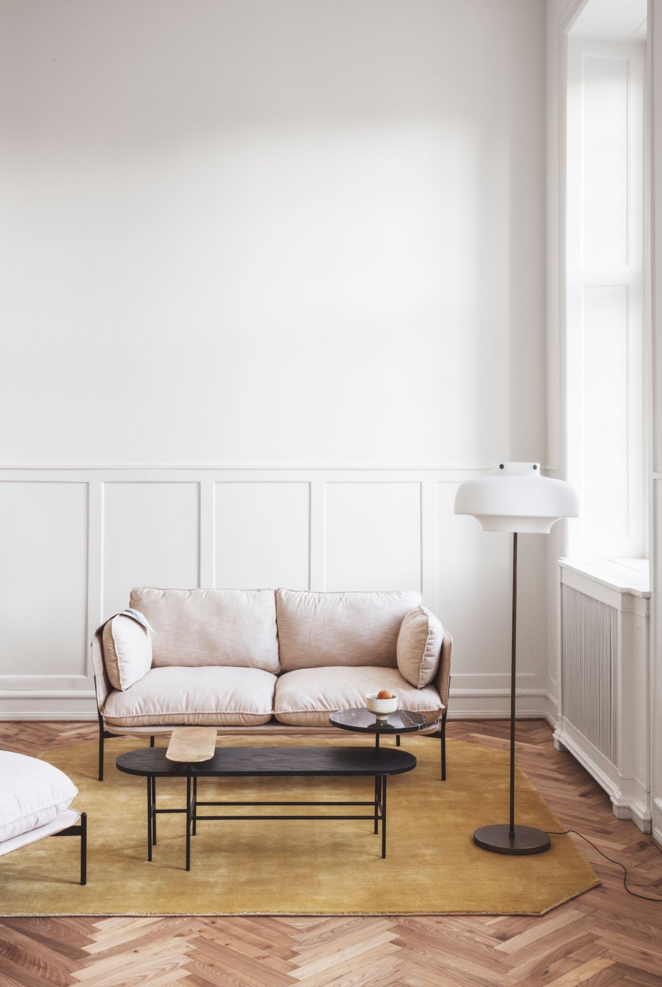 Beiges Cloud 2-Sitzer Sofa von AndTradition in minimalistischem Wohnzimmer mit Teppich, Tisch und Stehlampe.