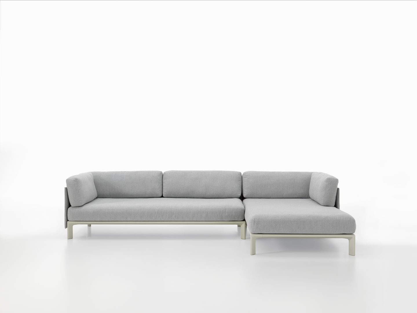 Graues Anagram Sofa von Vitra mit Ottomane und Rücken- sowie Seitenkissen auf weißem Hintergrund.