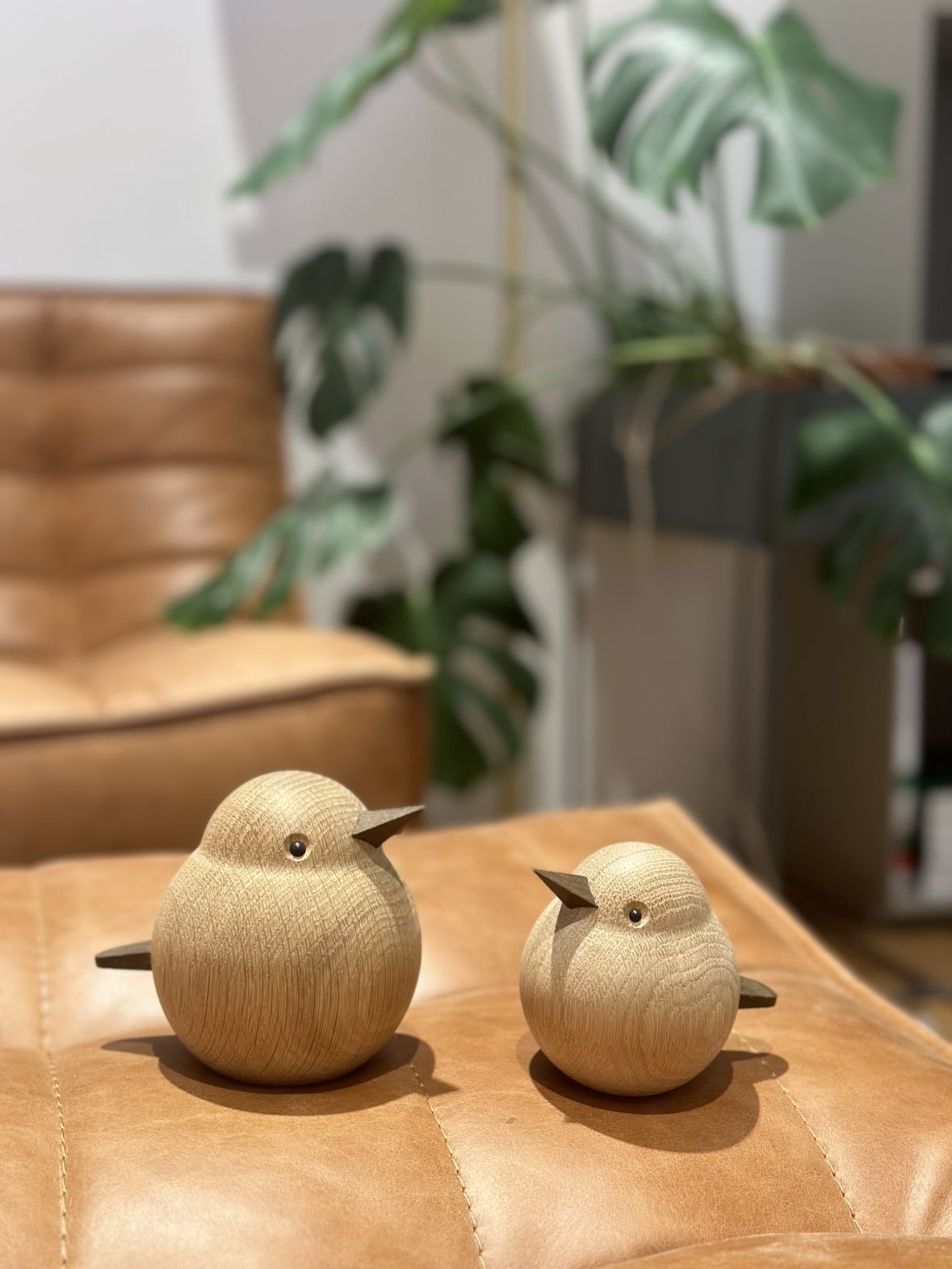 Zwei Holzfiguren, Papa Sparrow von Novoform, Eiche natur, als Dekoration auf Lederoberfläche.