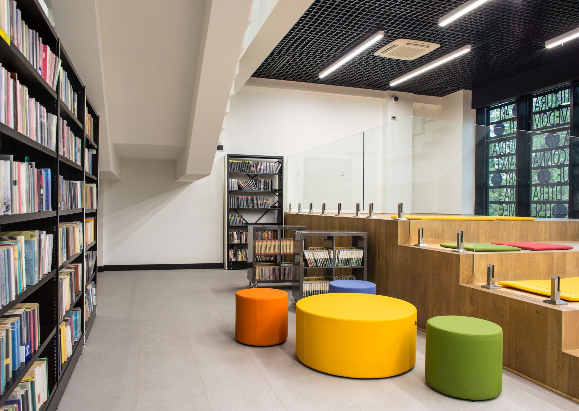 Bunte point POP R 450 Pouf Sitzhocker von Bejot mit Rollen in einer modernen Bibliothek.