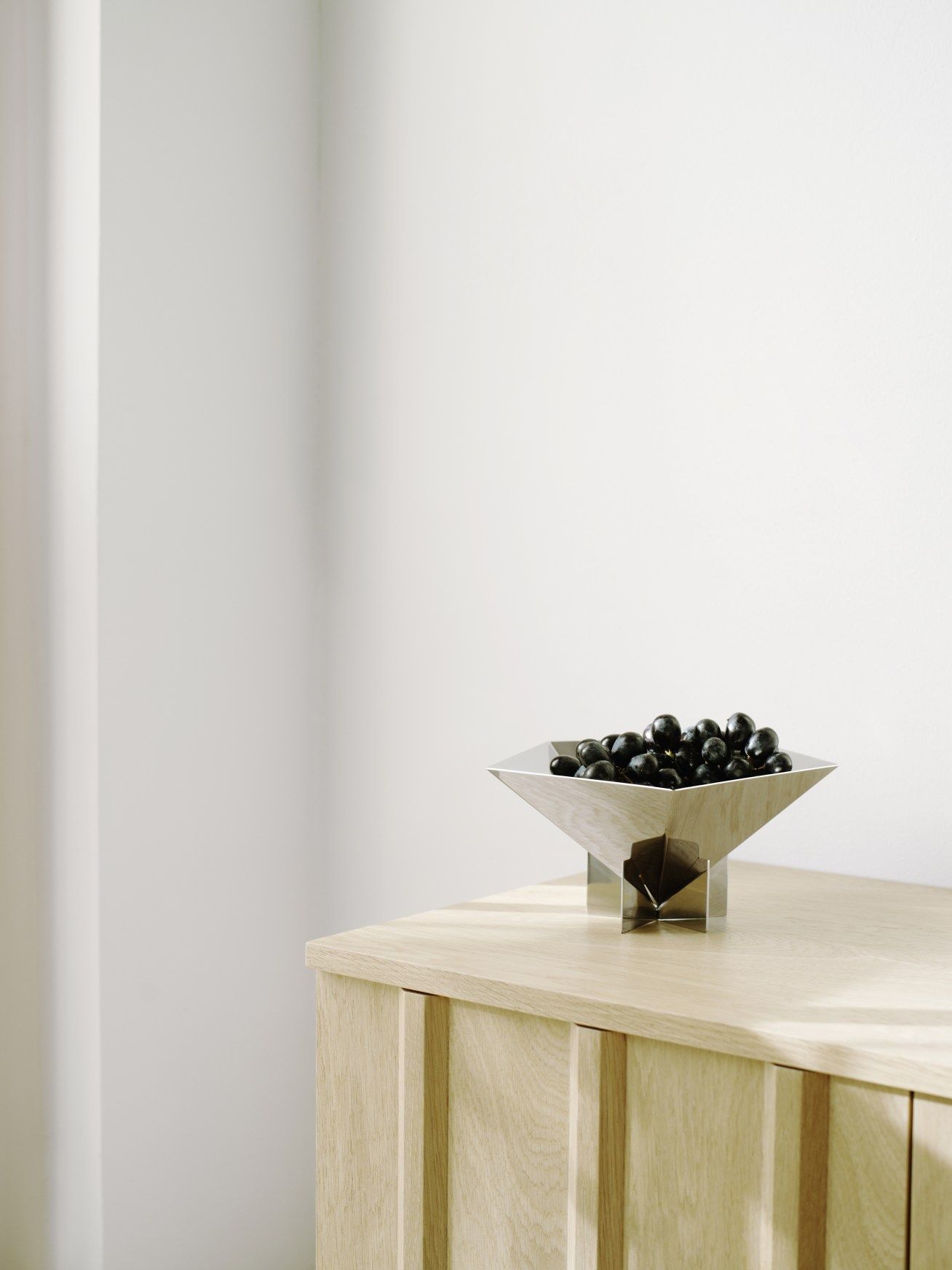 Nahaufnahme der Fem Schale von Normann Copenhagen aus Edelstahl, gefüllt mit dunklen Oliven.