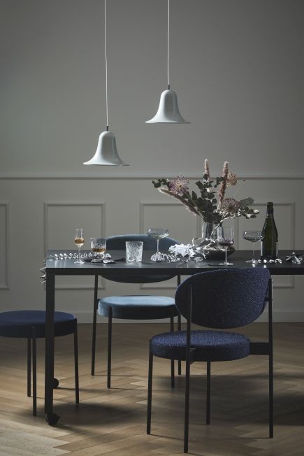Elegantes Esszimmer mit Panton Move Table Esstisch Rollbar von Verpan, blauen Stühlen und Pendelleuchten.