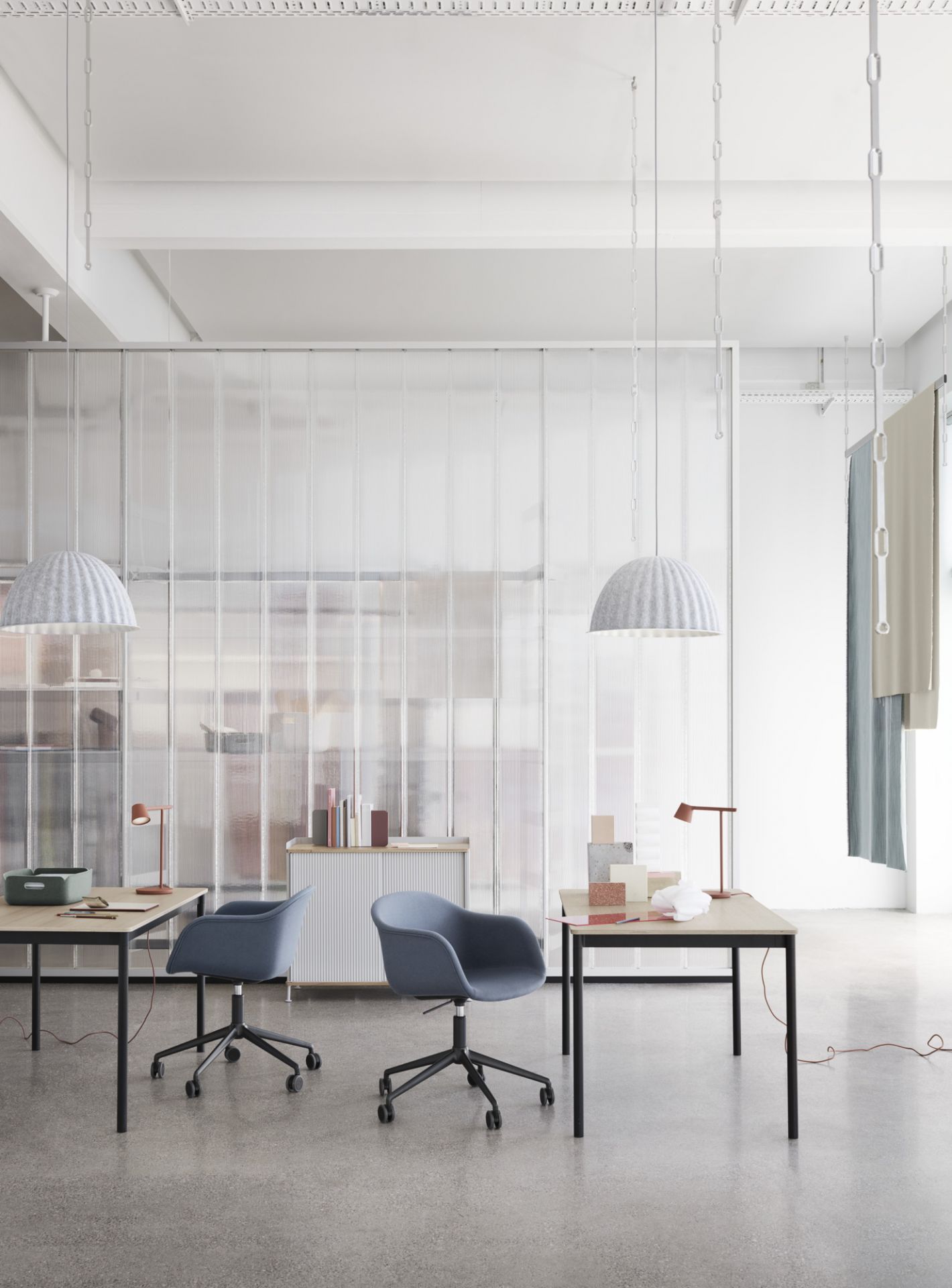 Zwei blaue, gepolsterte Fiber Armchairs von Muuto mit Drehfuß und Höhenverstellung an Schreibtischen.