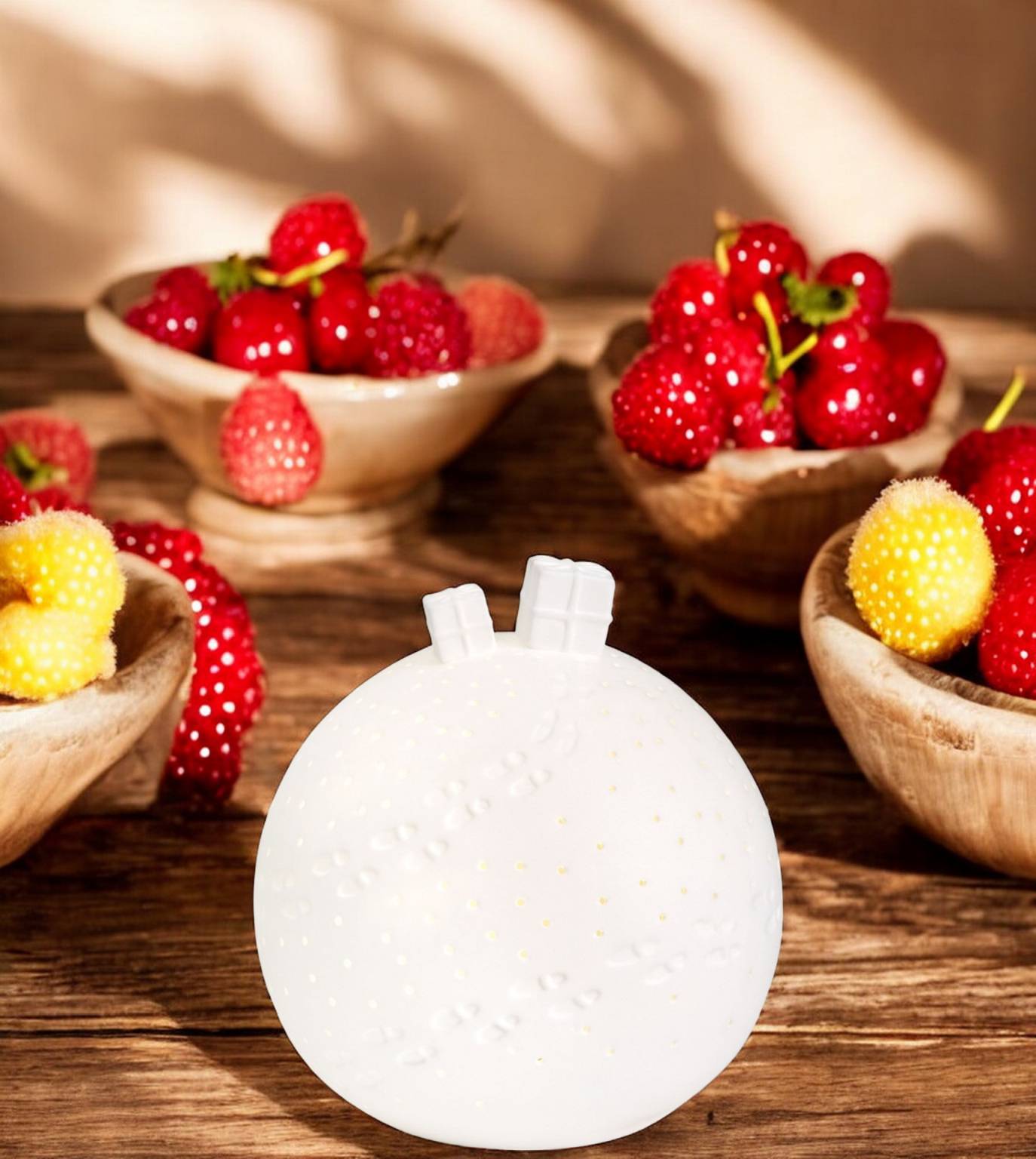 Weiße Porzellan Lichtkugel von Räder mit Geschenk-Motiv und LED-Beleuchtung auf Holztisch.