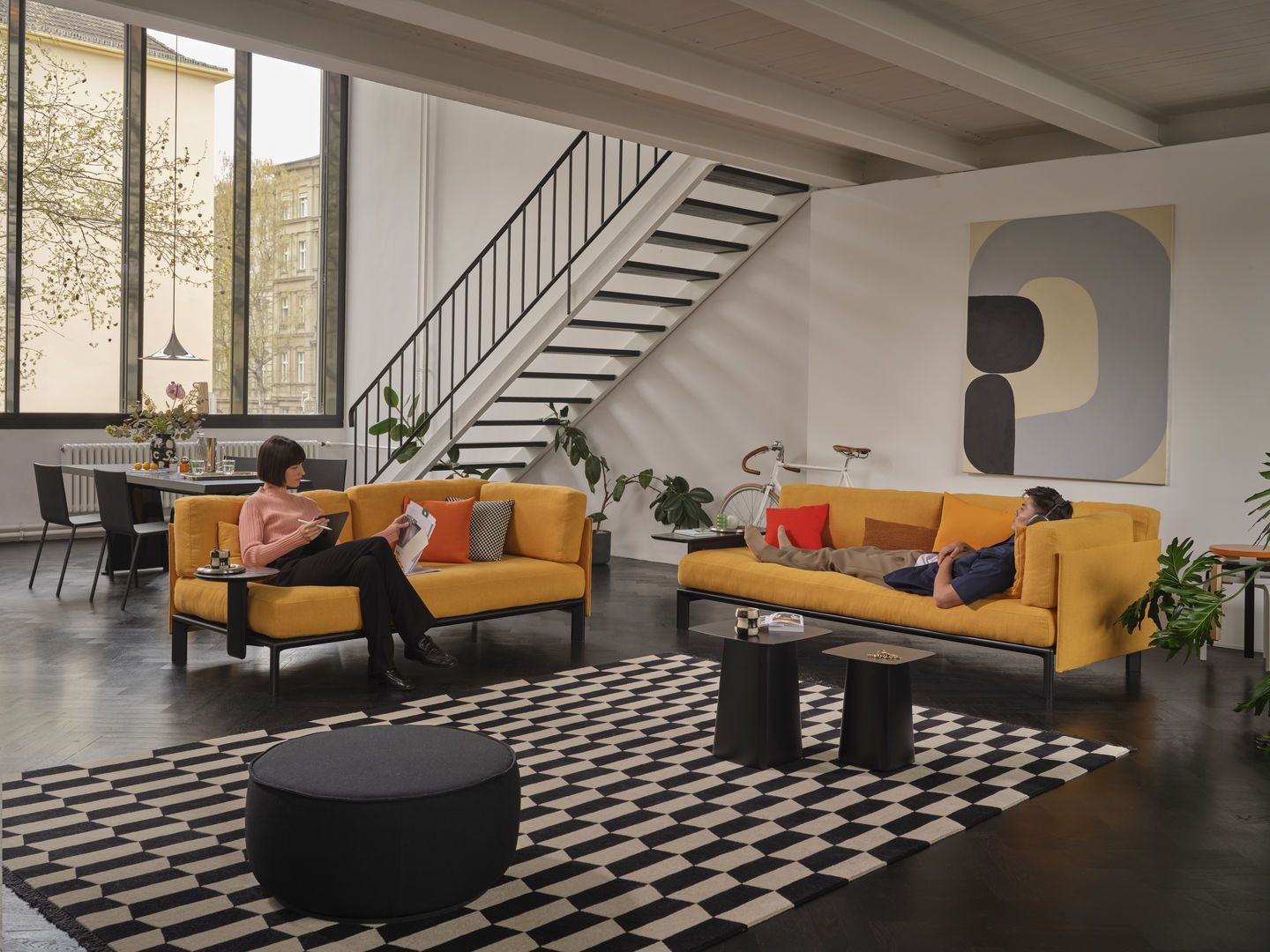 Wohnzimmer mit zwei gelben Sofas und zwei Anagram Anstecktischen von Vitra in Schwarz.
