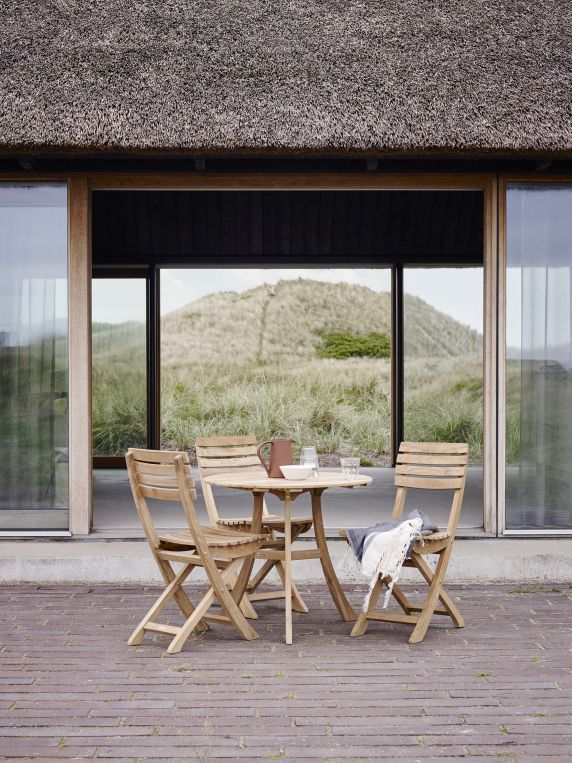 Vendia Klappstuhl von Skagerak by Fritz Hansen mit Gartentisch und Deko im Außenbereich.