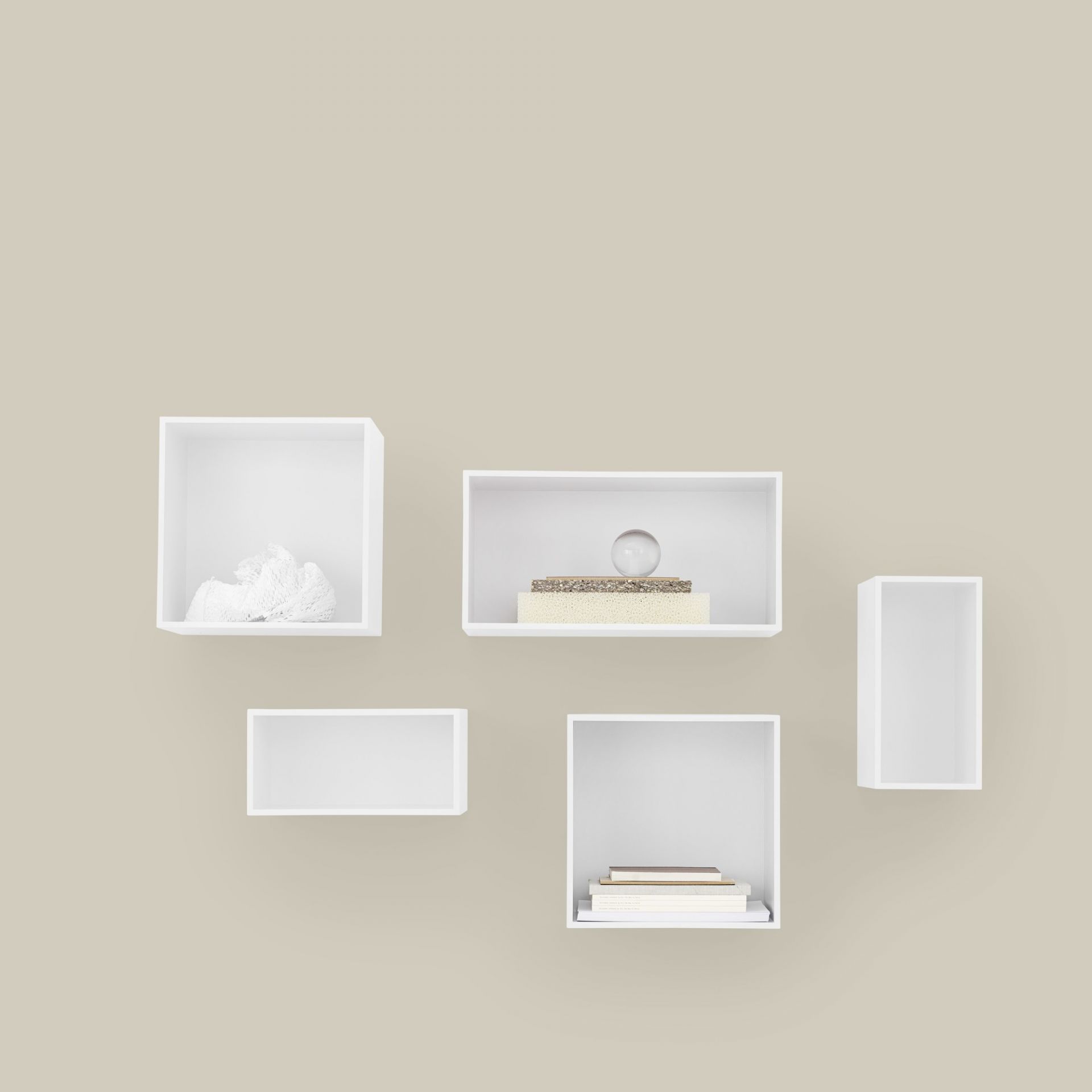 Weißes Muuto Mini Stacked Regalsystem 2.0 an beiger Wand mit Deko-Objekten und Büchern.