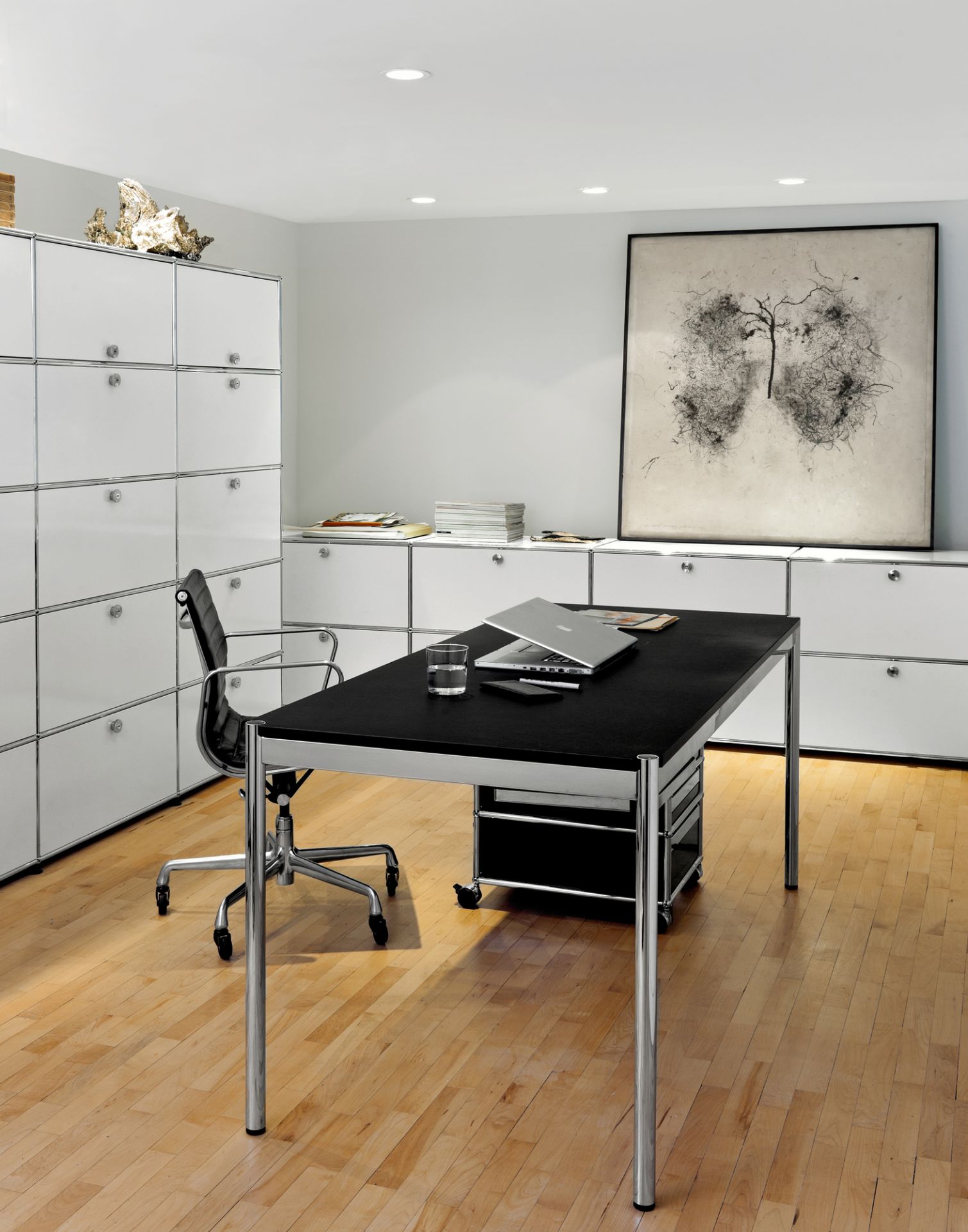 USM Haller Tisch mit schwarzer Tischplatte und Chromgestell in einem modernen Büroambiente.