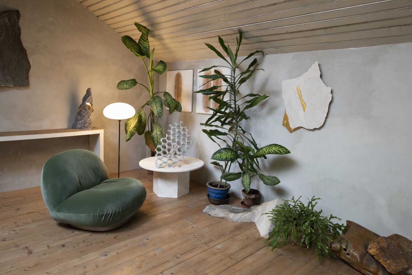 Wohnzimmer mit Gubi Epic Couchtisch, grünem Sessel und Zimmerpflanzen auf hellem Holzboden.