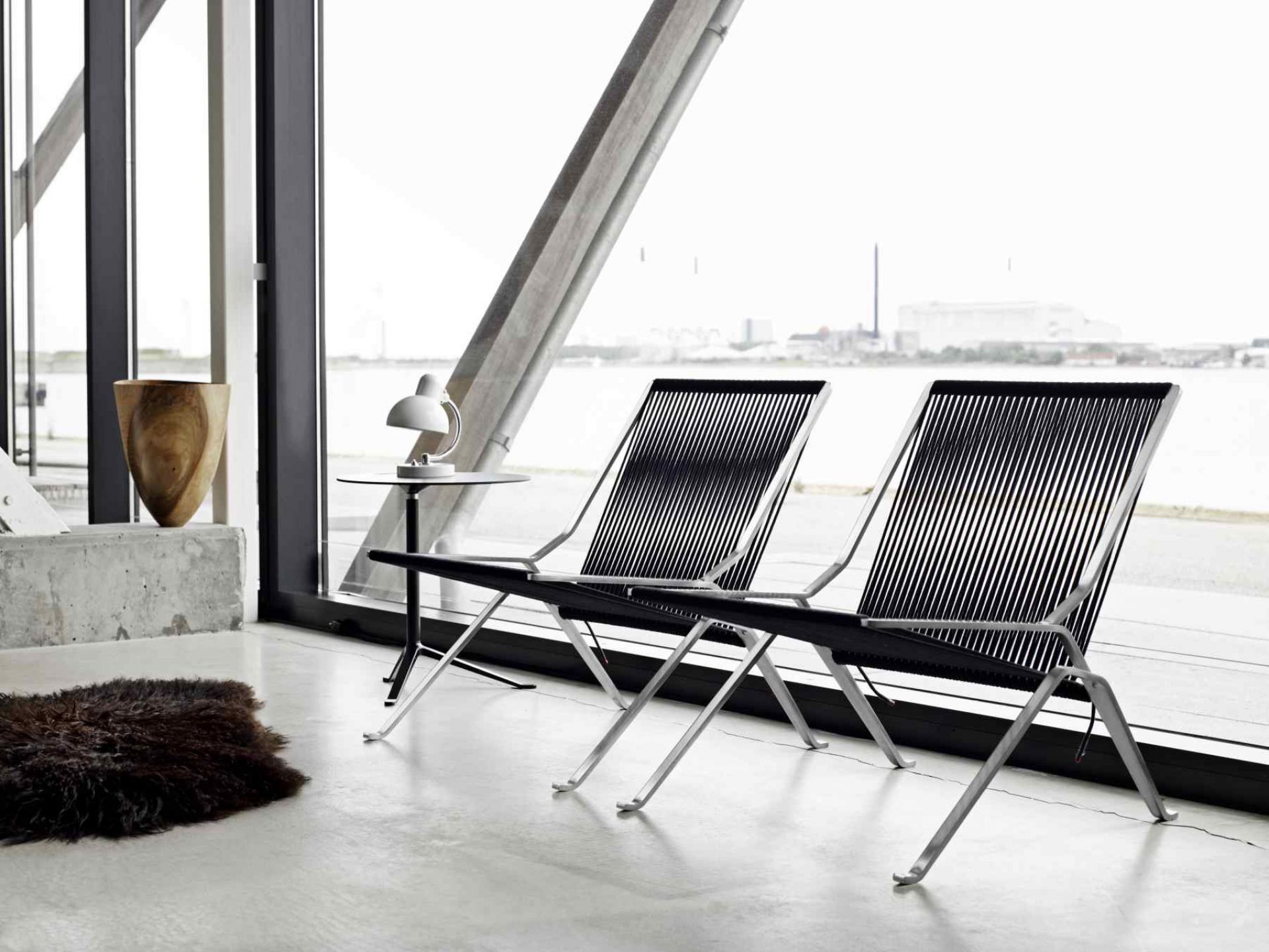 Zwei PK25 Sessel von Fritz Hansen vor einem Fenster mit Blick auf eine Stadt am Wasser.