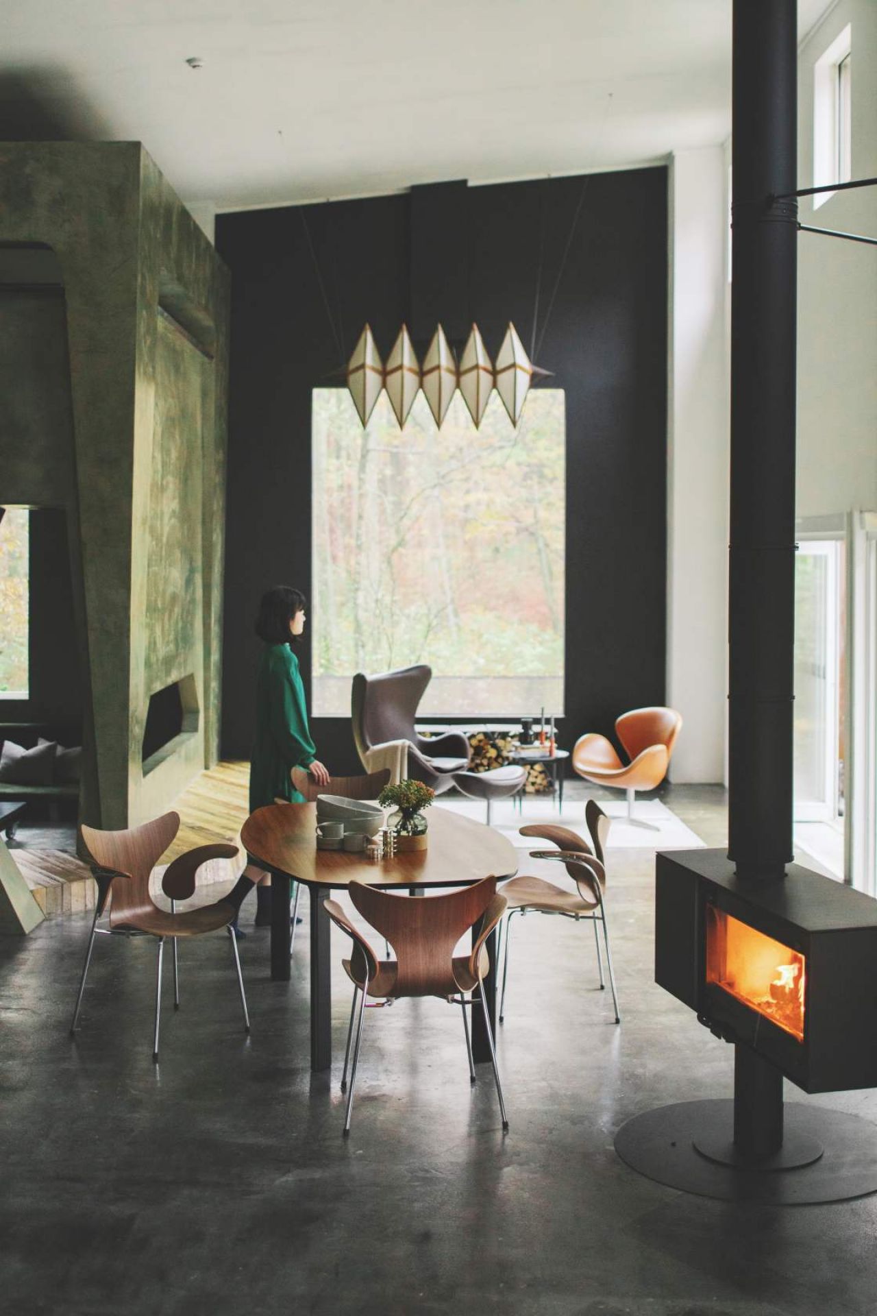 Innenaufnahme mit Fritz Hansen Lily Armlehnstühlen aus Holz um einen Esstisch in modernem Wohnraum.