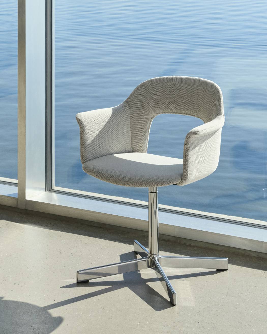 Layout Armchair von Hay, ein moderner Bürostuhl mit Armlehnen und Drehfuß vor einem Fenster.