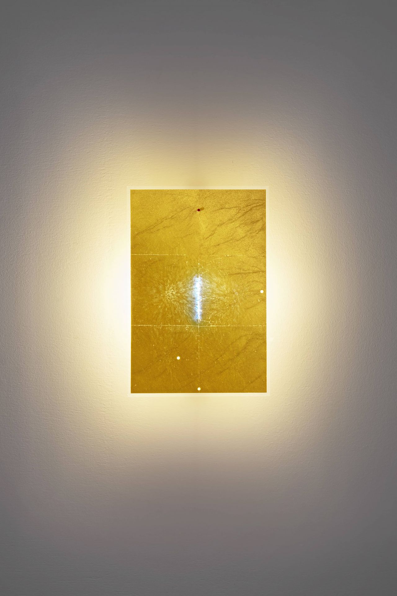 24 Karat Blau Wandleuchte von Ingo Maurer: Goldene, rechteckige Wandlampe mit bläulichem Lichteffekt.