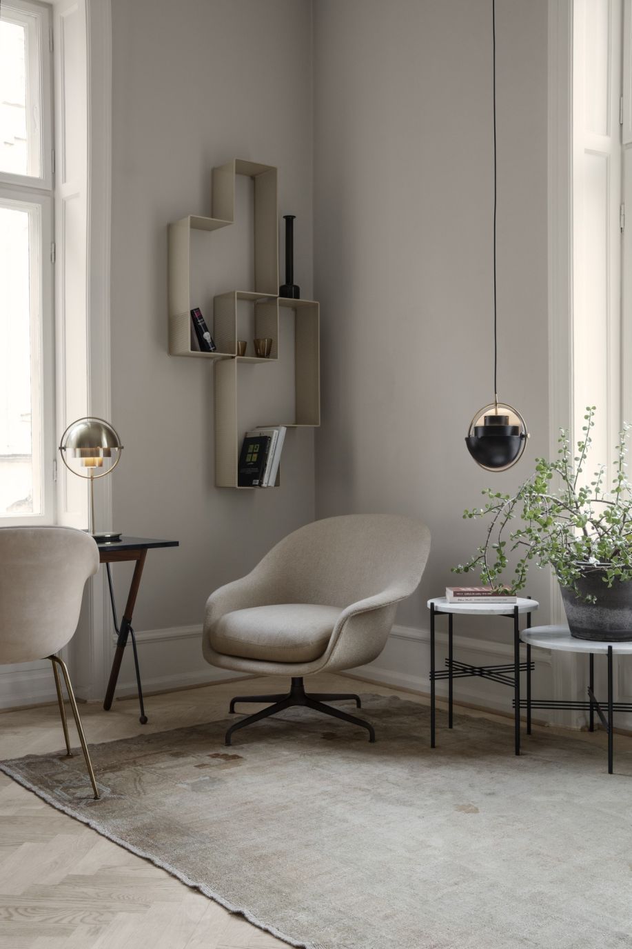 Interieur mit Gubi Multi-Lite Pendelleuchte in Chrom, die über einem Sessel hängt.
