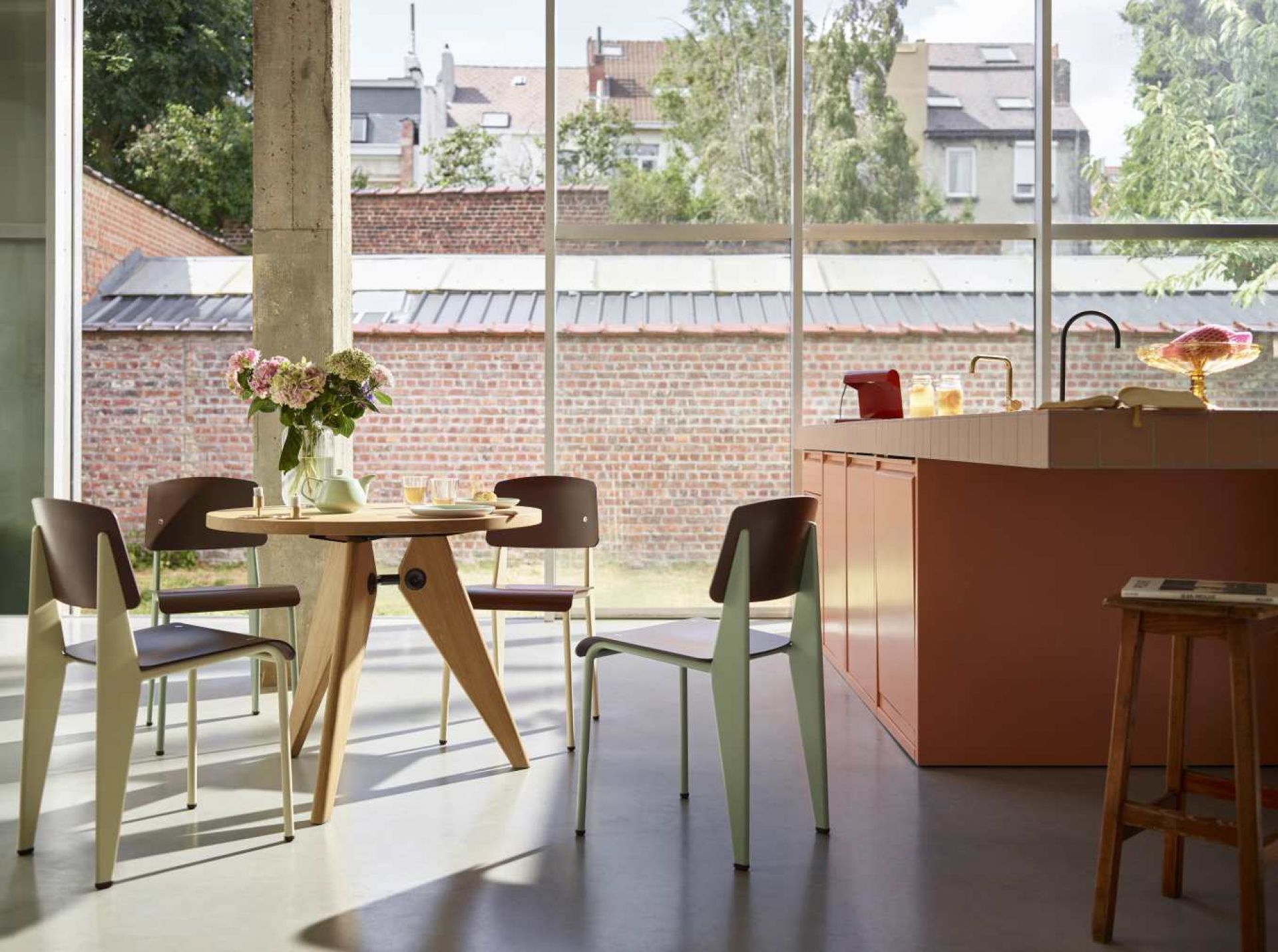 Vitra Guéridon Tisch mit Holzgestell und runder Tischplatte, umgeben von Stühlen in modernem Ambiente.