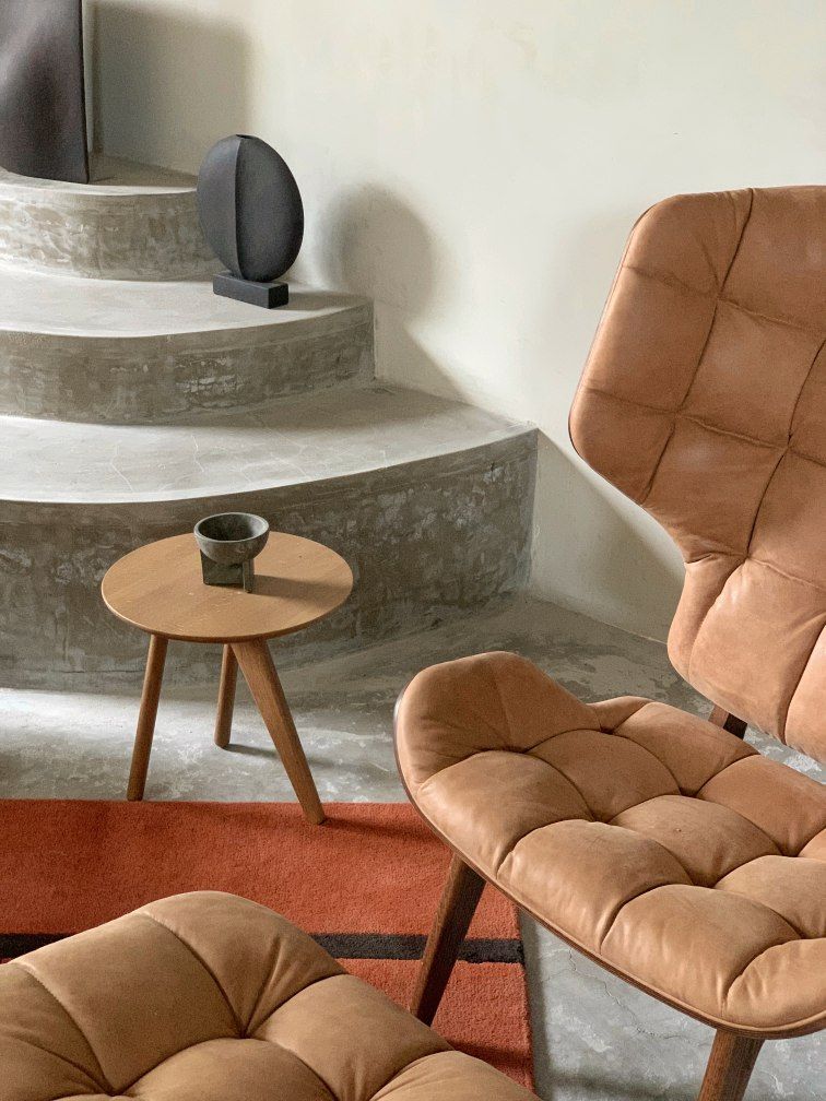 NORR11 Mammoth Chair Sessel aus braunem Leder mit Steppung und passendem Hocker auf Teppich.