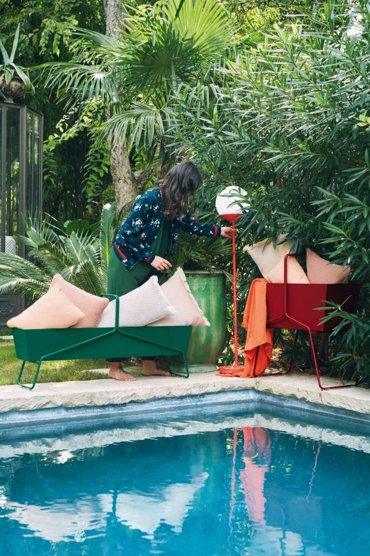 Basket Blumenkasten lang von Fermob in Grün und Rot am Pool mit Kissen und Frau.