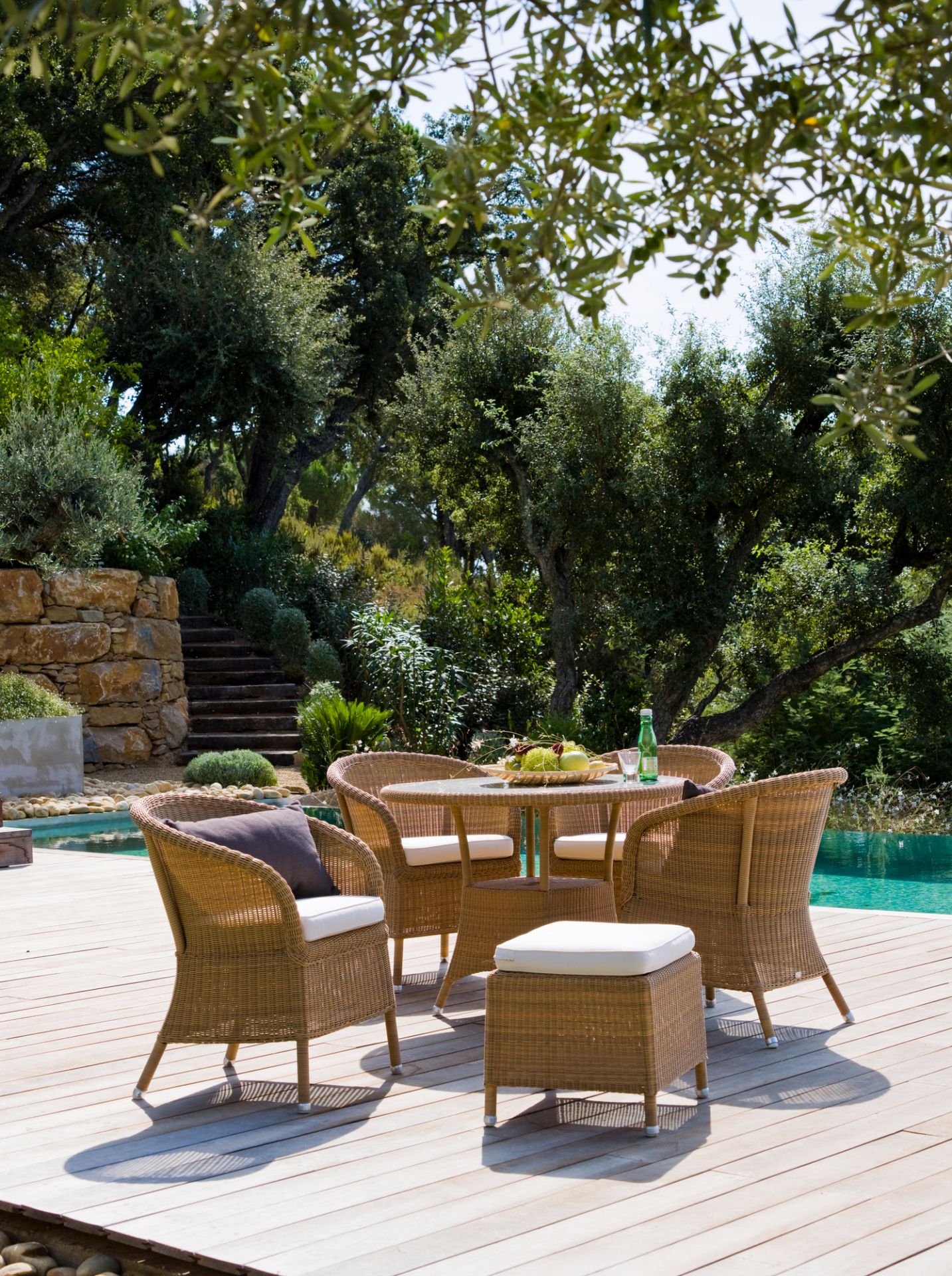 Derby Outdoor Sessel von Cane-Line aus Rattan mit Tisch und Hocker auf Holzterrasse.