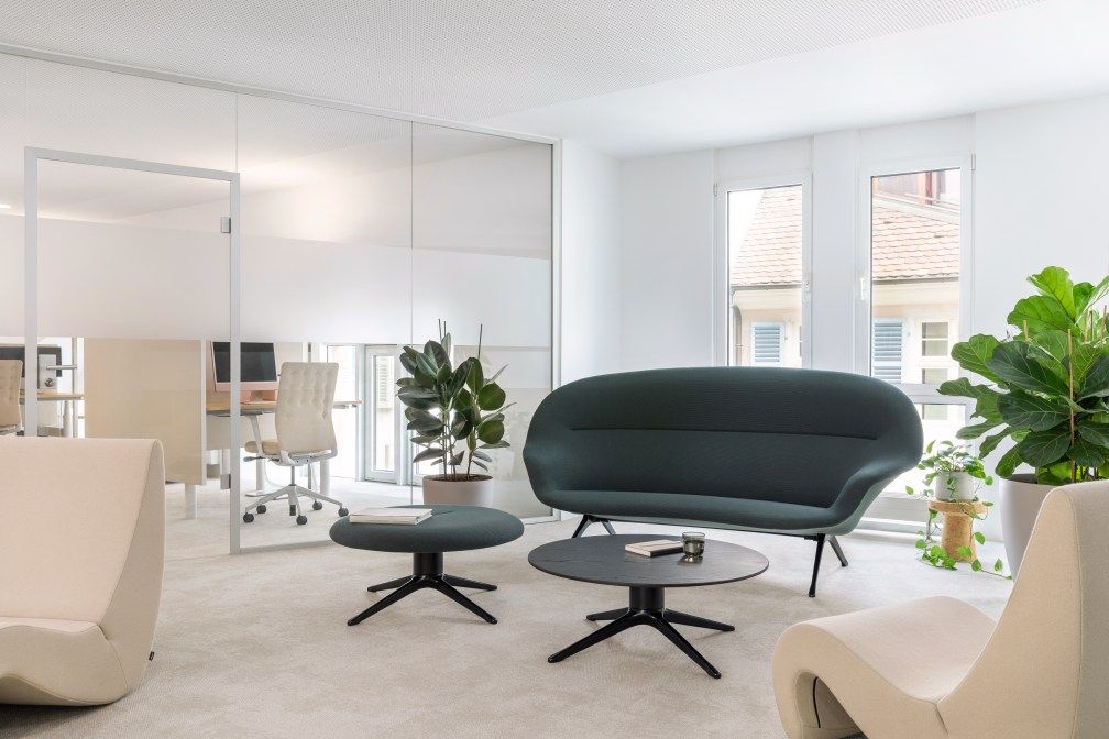 Abalon Sofa von Vitra in modernem Büro-Lounge-Bereich mit Sesseln, Tisch und Pflanzen.
