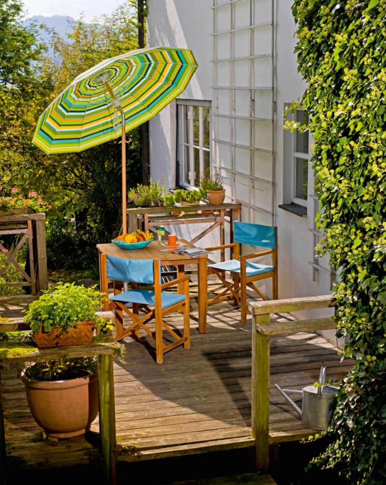 Cabin Sessel von Weishäupl aus Tanne auf einer Holzterrasse mit Tisch und Sonnenschirm.