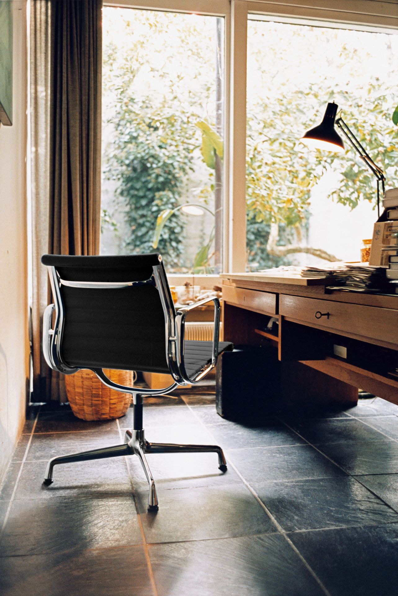 Vitra Aluminium Chair EA 108 in Schwarz vor einem Schreibtisch und Fenster.