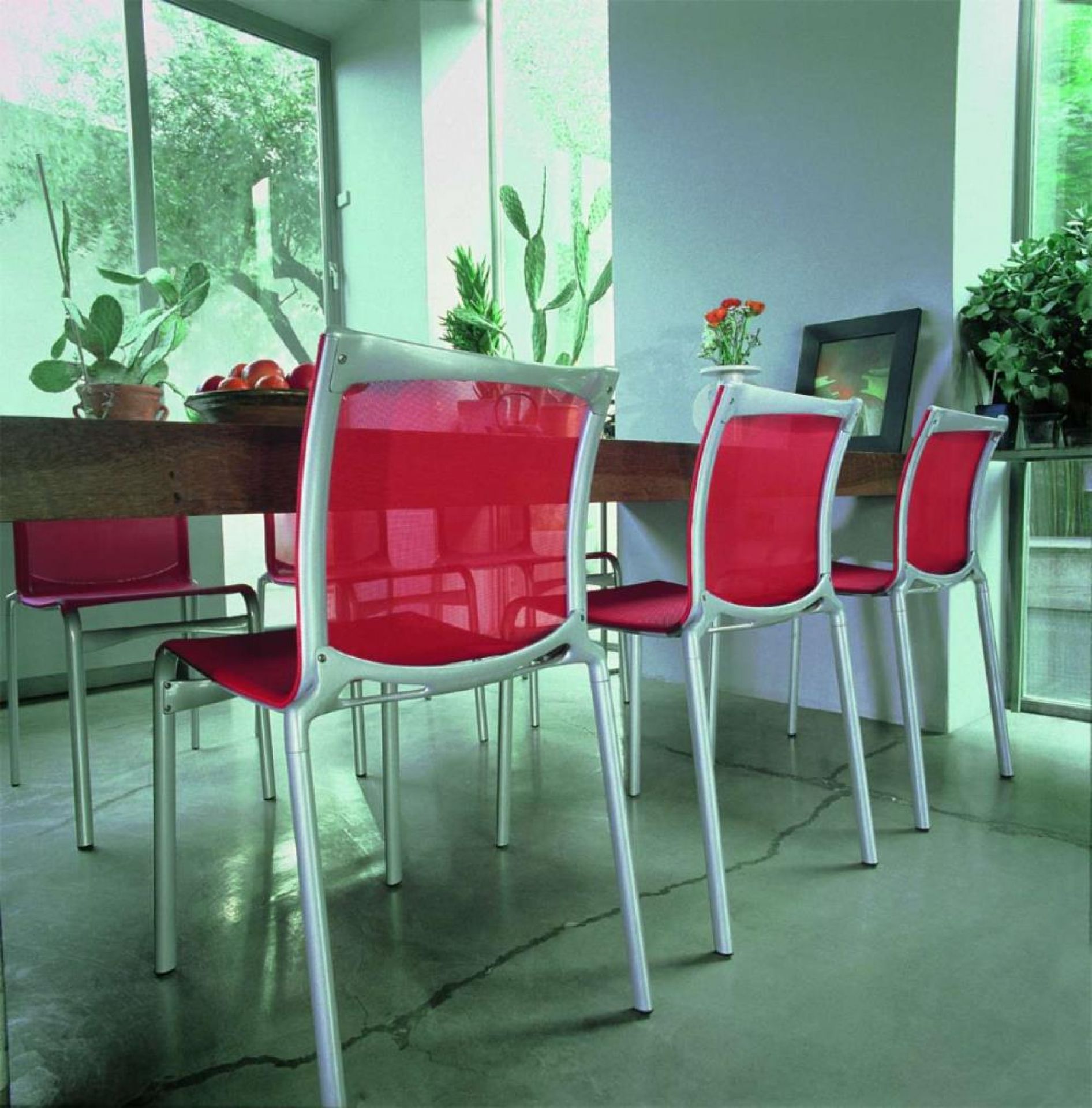 Bigframe Stühle in Rot und Silber um einen Holztisch in modernem Interieur.