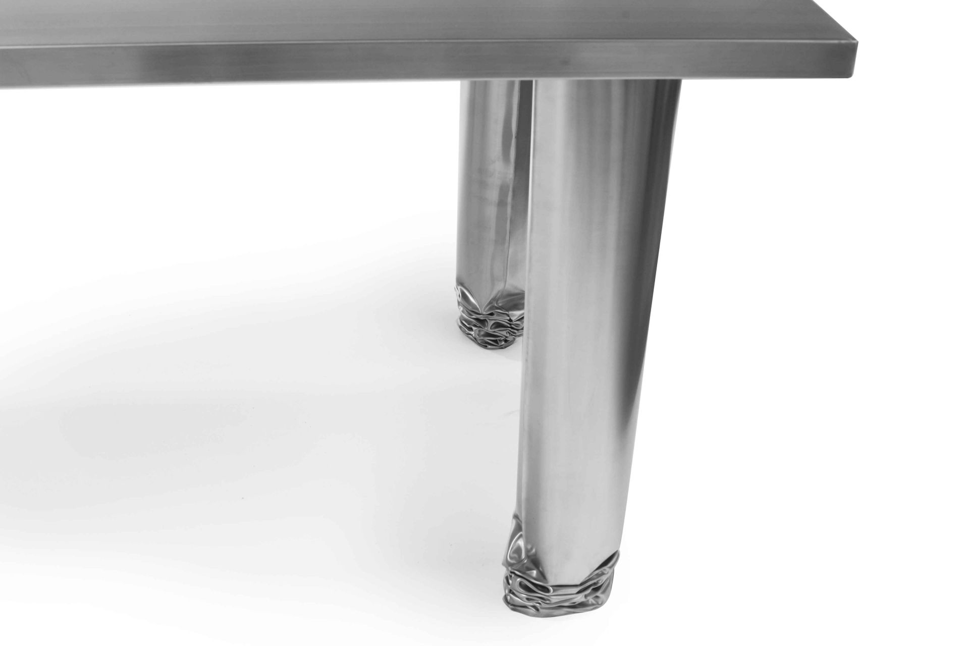 Detailaufnahme des Zieta Crash Table Esstischs mit polierten Edelstahlbeinen und Tischplatte.