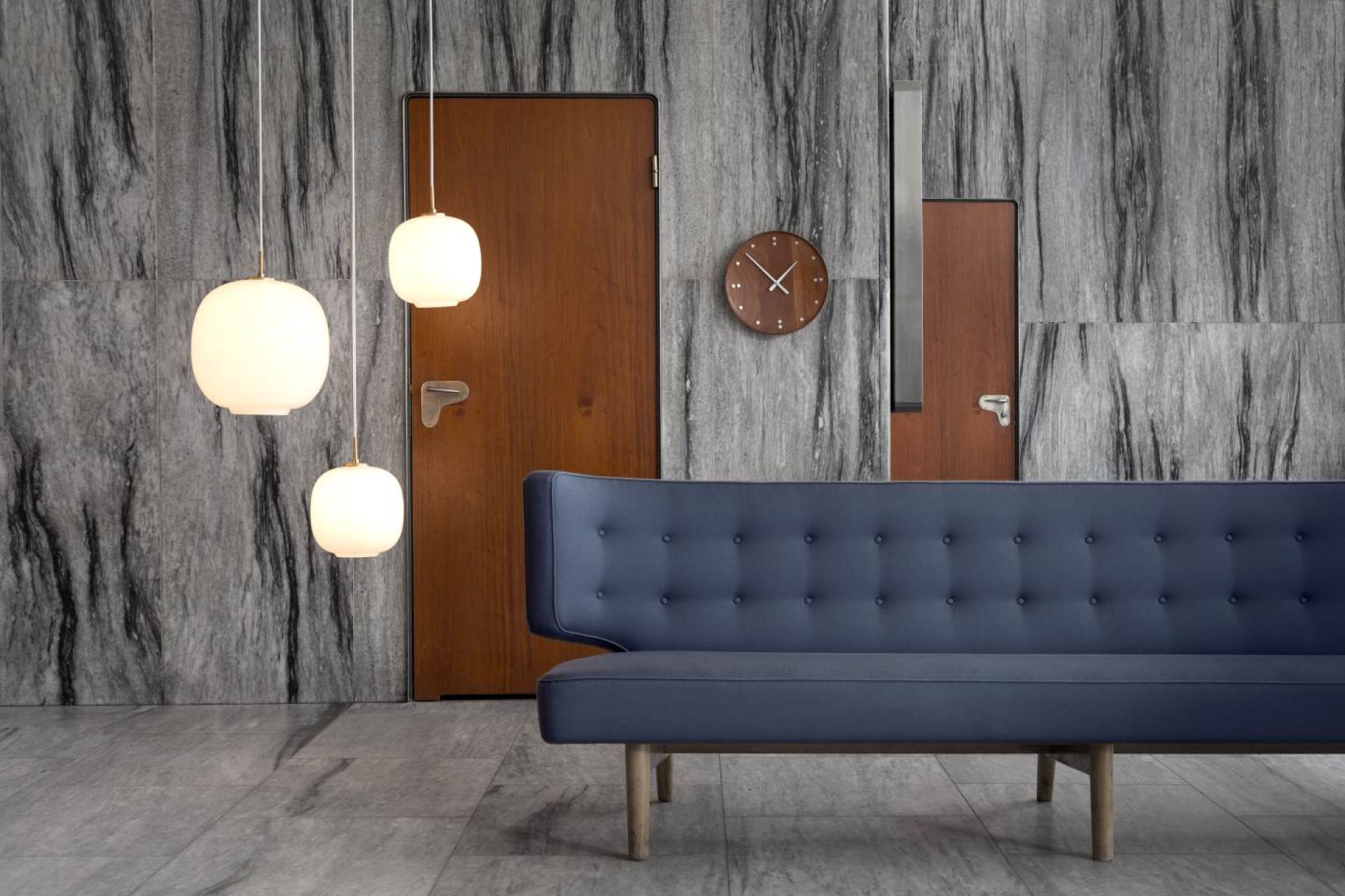 Drei VL45 Radiohus Pendelleuchten von Louis Poulsen über einem blauen Sofa in einem modernem Wohnzimmer.