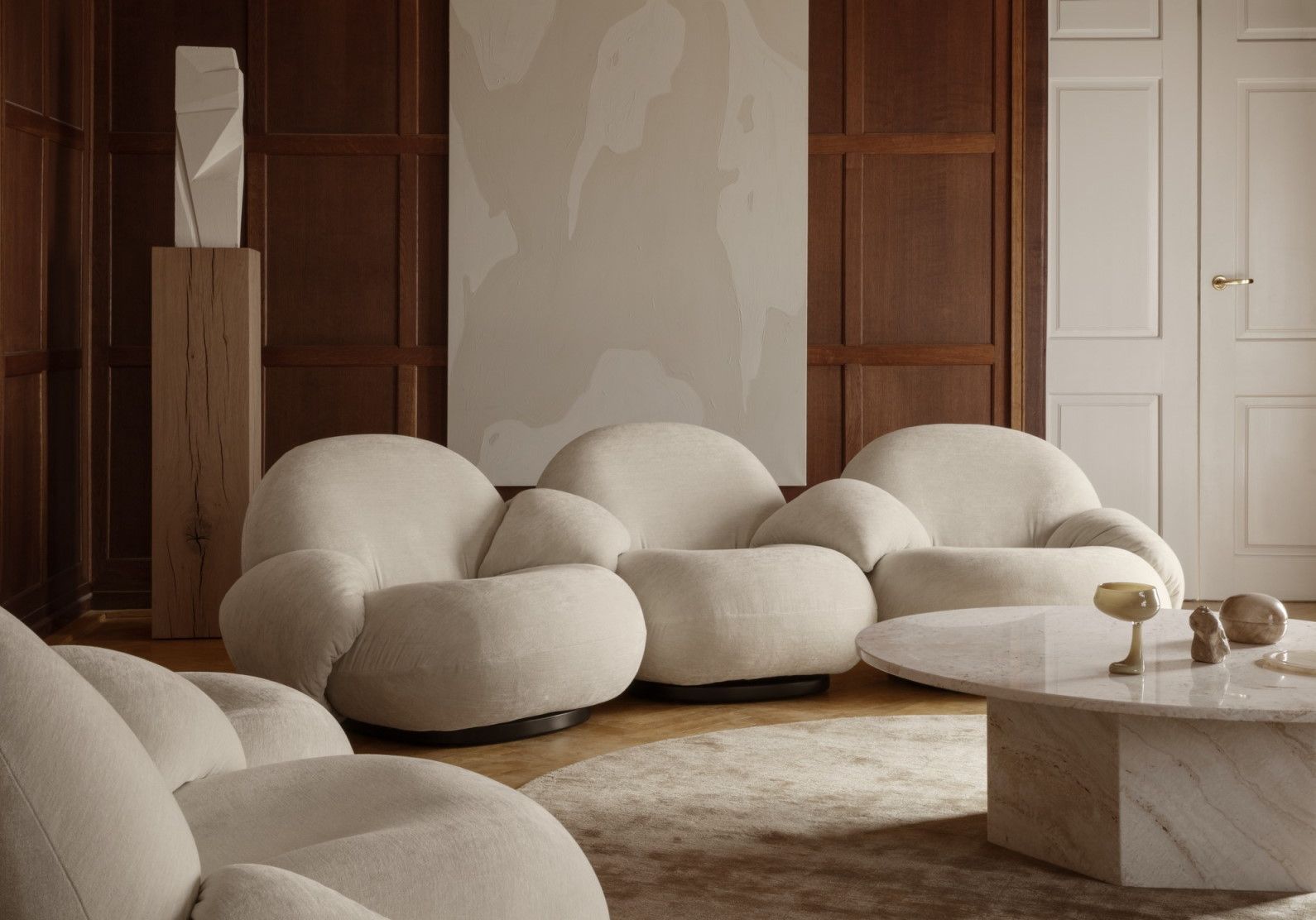Wohnzimmer mit beigen Sesseln und Gubi Epic Couchtisch aus Travertin Marmor.
