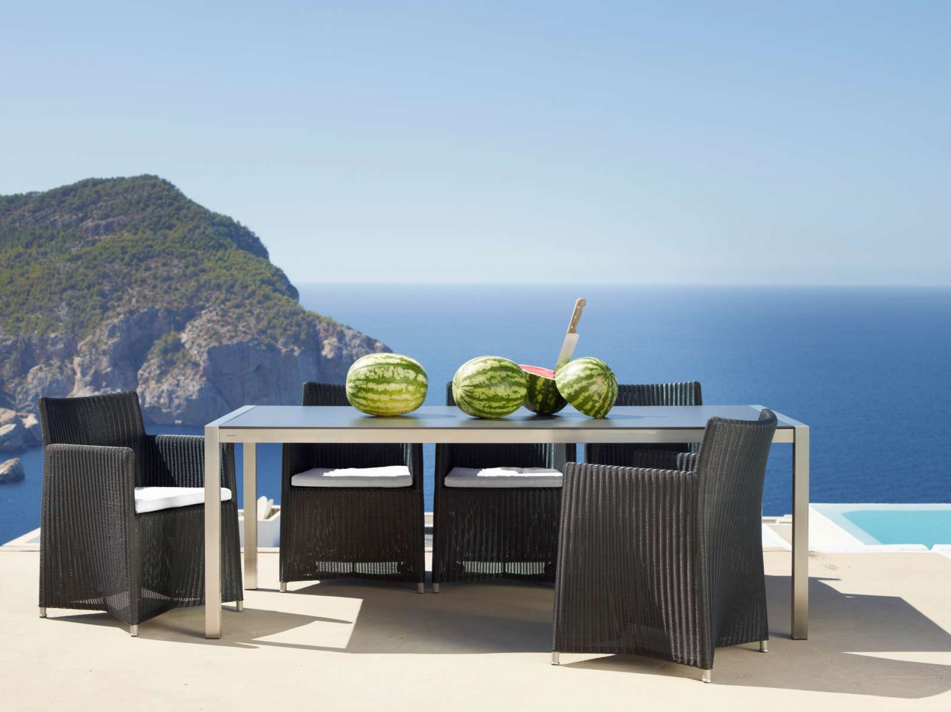 Graphitfarbener Cane-Line Diamond Lounge Sessel aus Rattan mit Tisch und Meerblick. Outdoor Möbel.