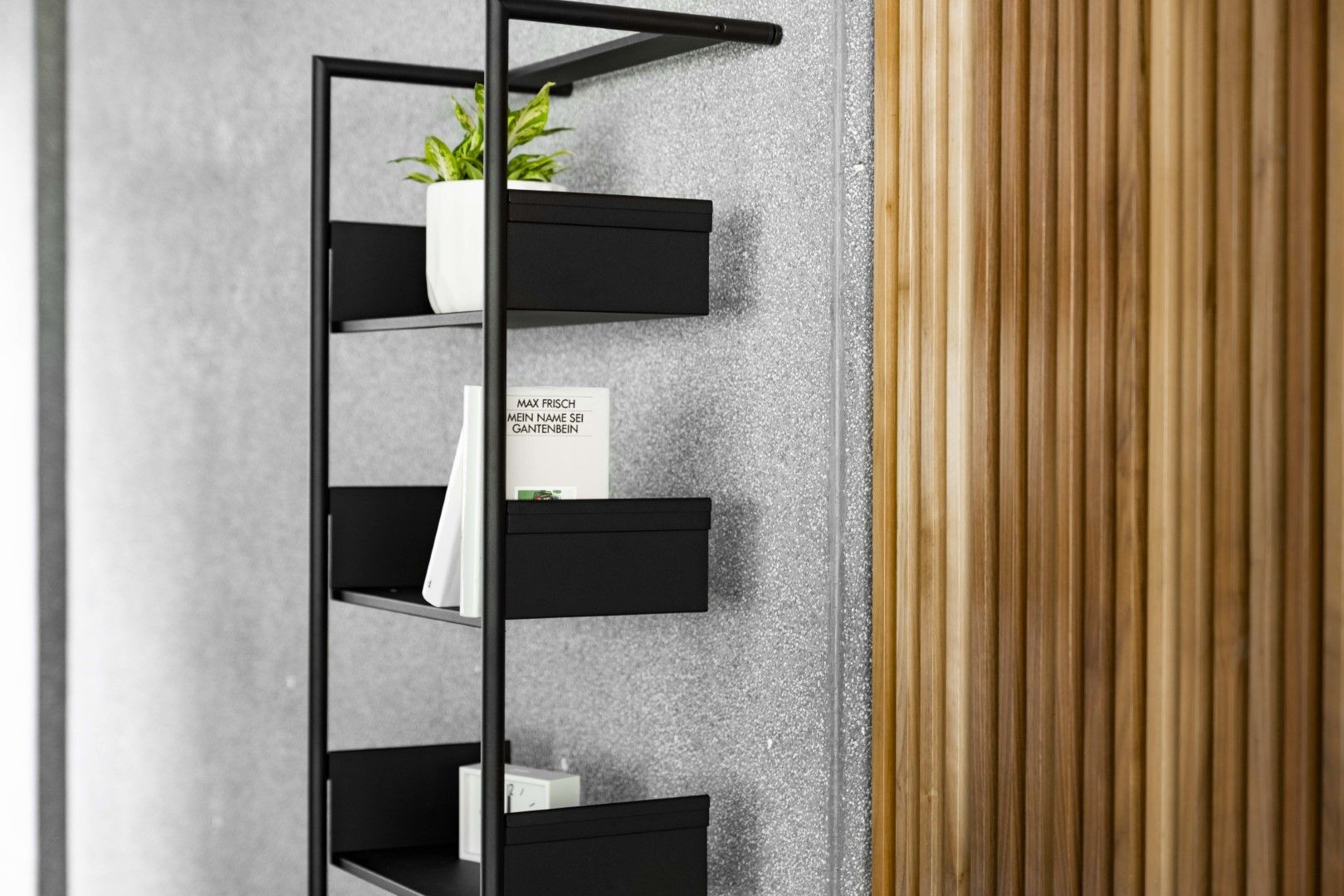 Schwarzes Pool 196 Medium Anlehnregal von Mox mit Pflanze, Buch und Dekoration vor Wand.