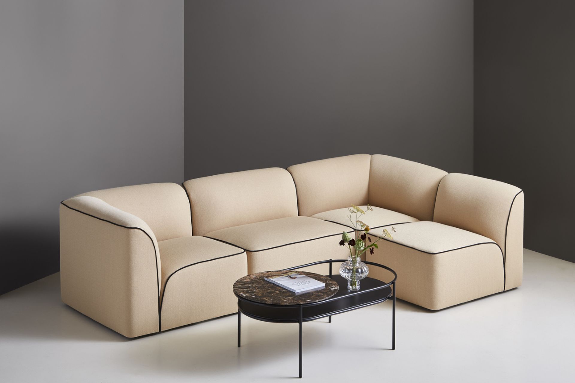 Beige Flora Modul-Sofa mit schwarzer Paspelierung und passendem Couchtisch im modernen Wohnzimmer.